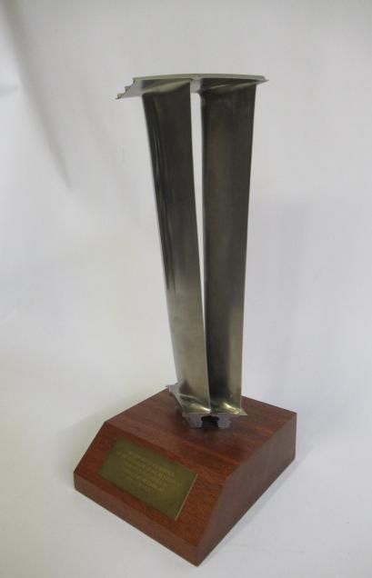 Two turbine blades from a Rolls Royce gas turbine engine mounted on wooden base with retirement Image