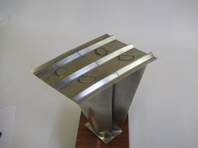 Two turbine blades from a Rolls Royce gas turbine engine mounted on wooden base with retirement Image