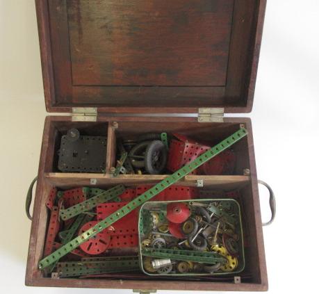 A wooden box containing a quantity of playworn red and green Meccano including two clockwork motors Image