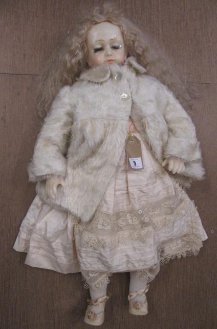 A modern wax head and shoulders doll with half closed brown glass eyes Image