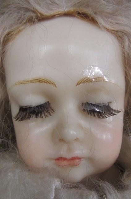 A modern wax head and shoulders doll with half closed brown glass eyes Image