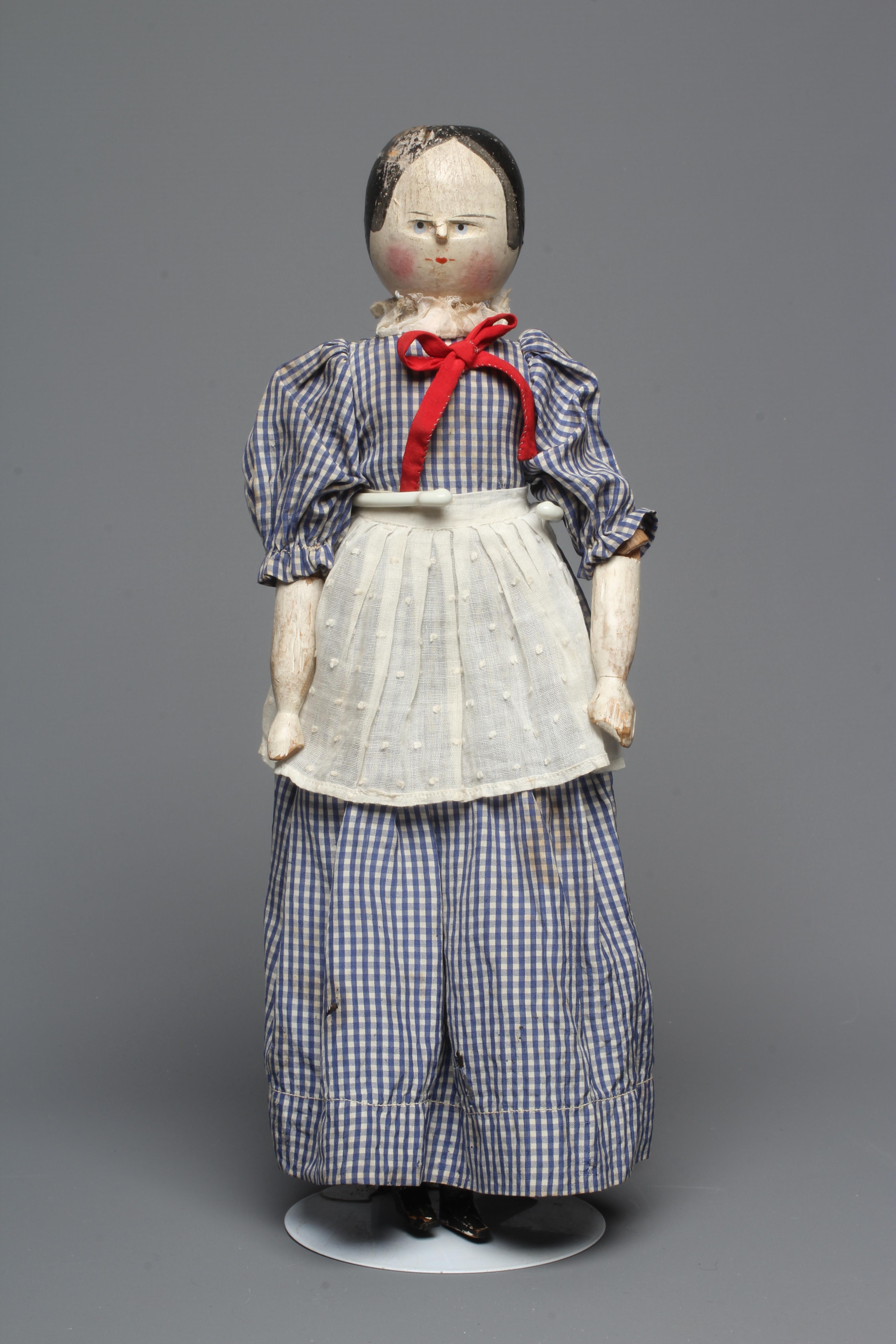 An antique peg doll, with carved and painted face, shaped body, jointed limbs, painted shoes and Image