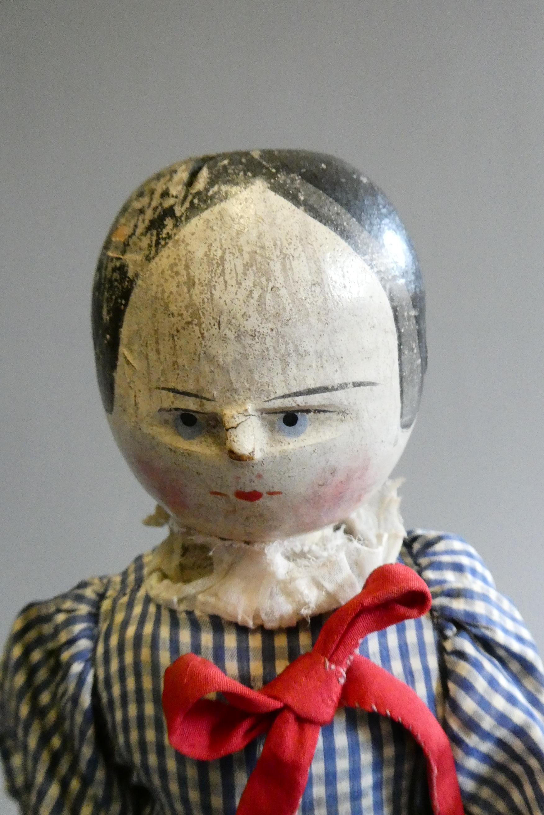 An antique peg doll, with carved and painted face, shaped body, jointed limbs, painted shoes and Image
