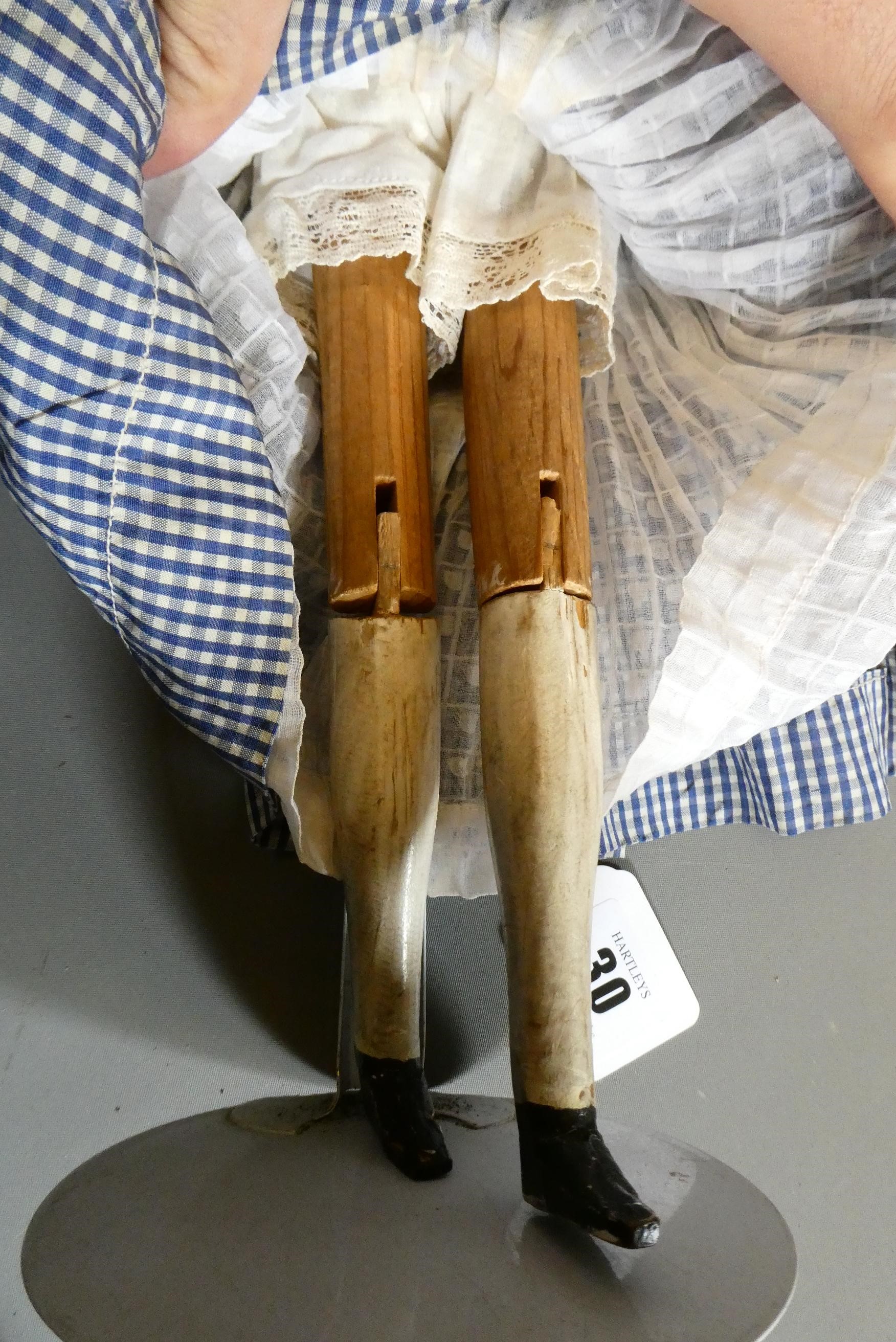 An antique peg doll, with carved and painted face, shaped body, jointed limbs, painted shoes and Image