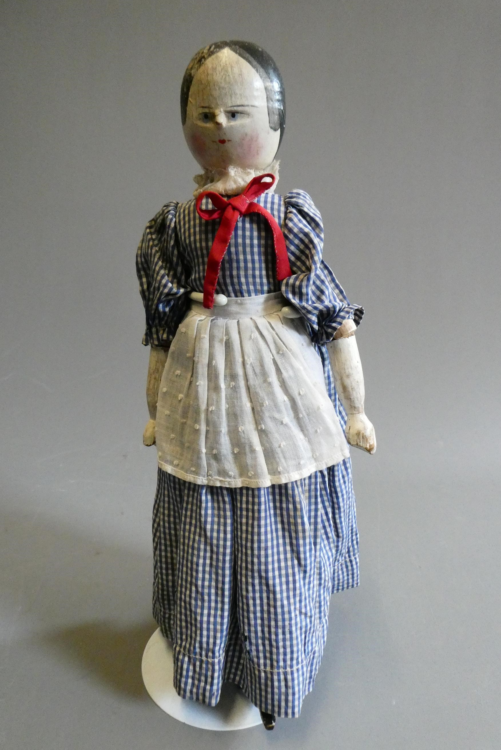 An antique peg doll, with carved and painted face, shaped body, jointed limbs, painted shoes and Image