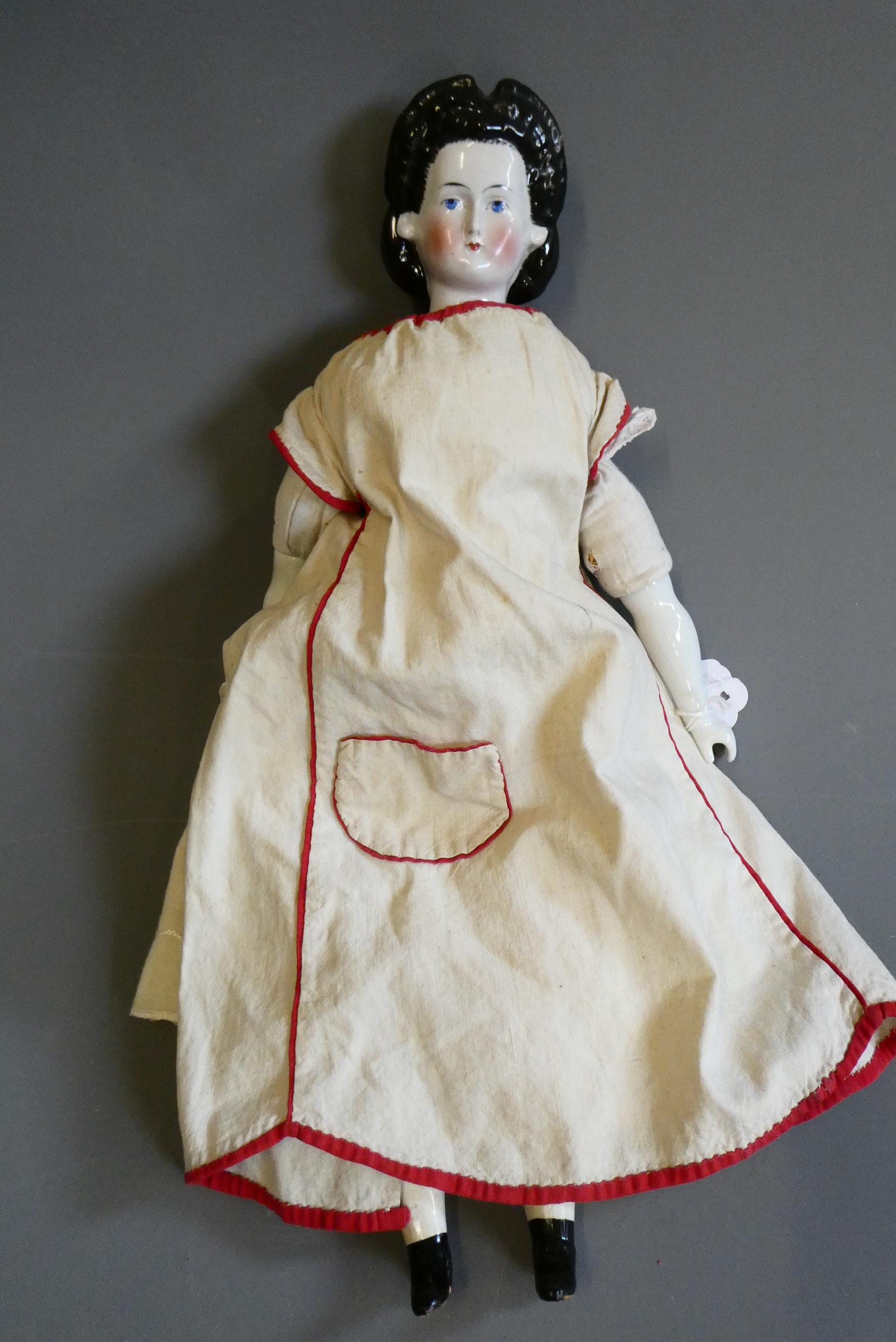A Victorian china shoulder head doll, with painted features, moulded hair, fabric body, ceramic Image