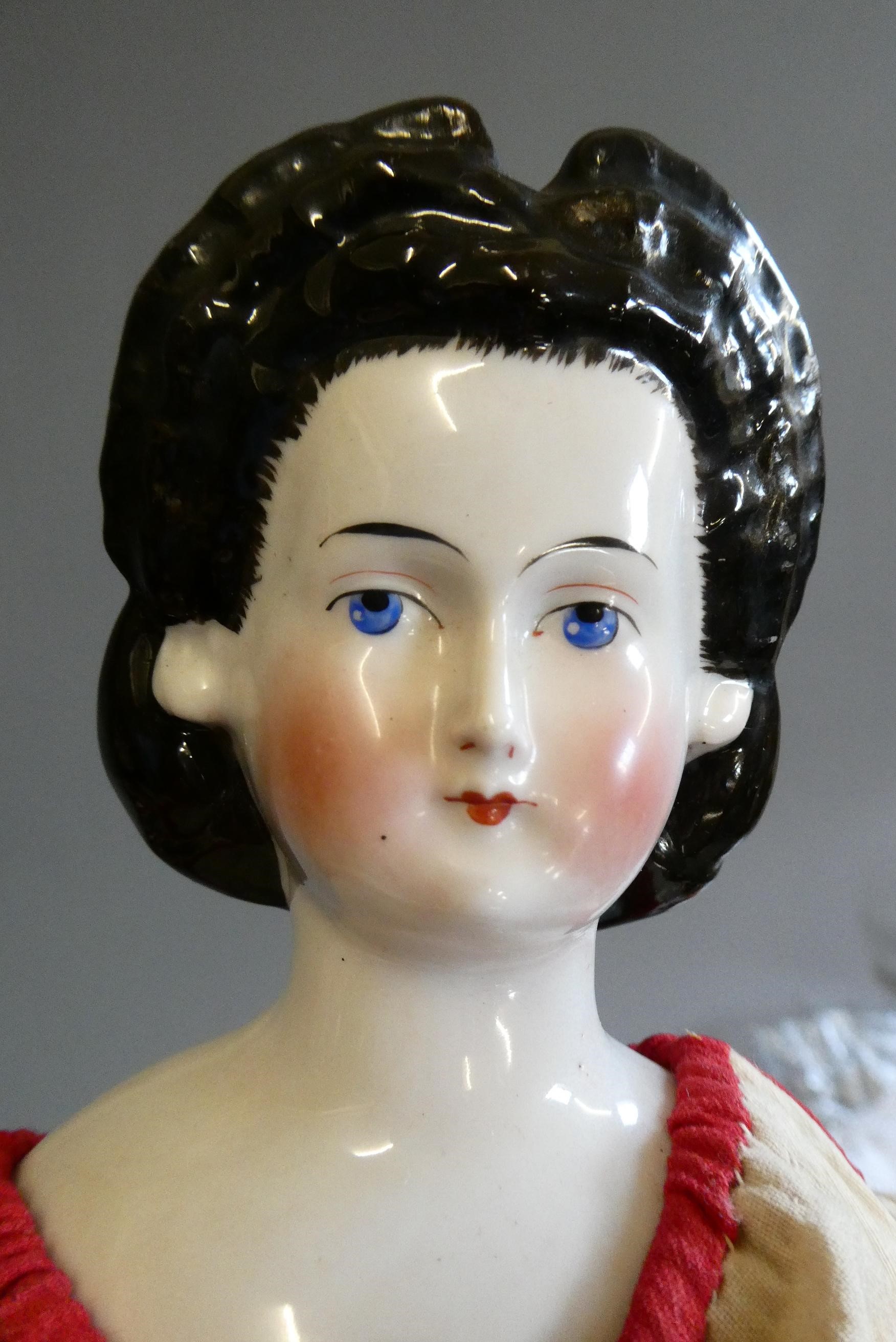 A Victorian china shoulder head doll, with painted features, moulded hair, fabric body, ceramic Image