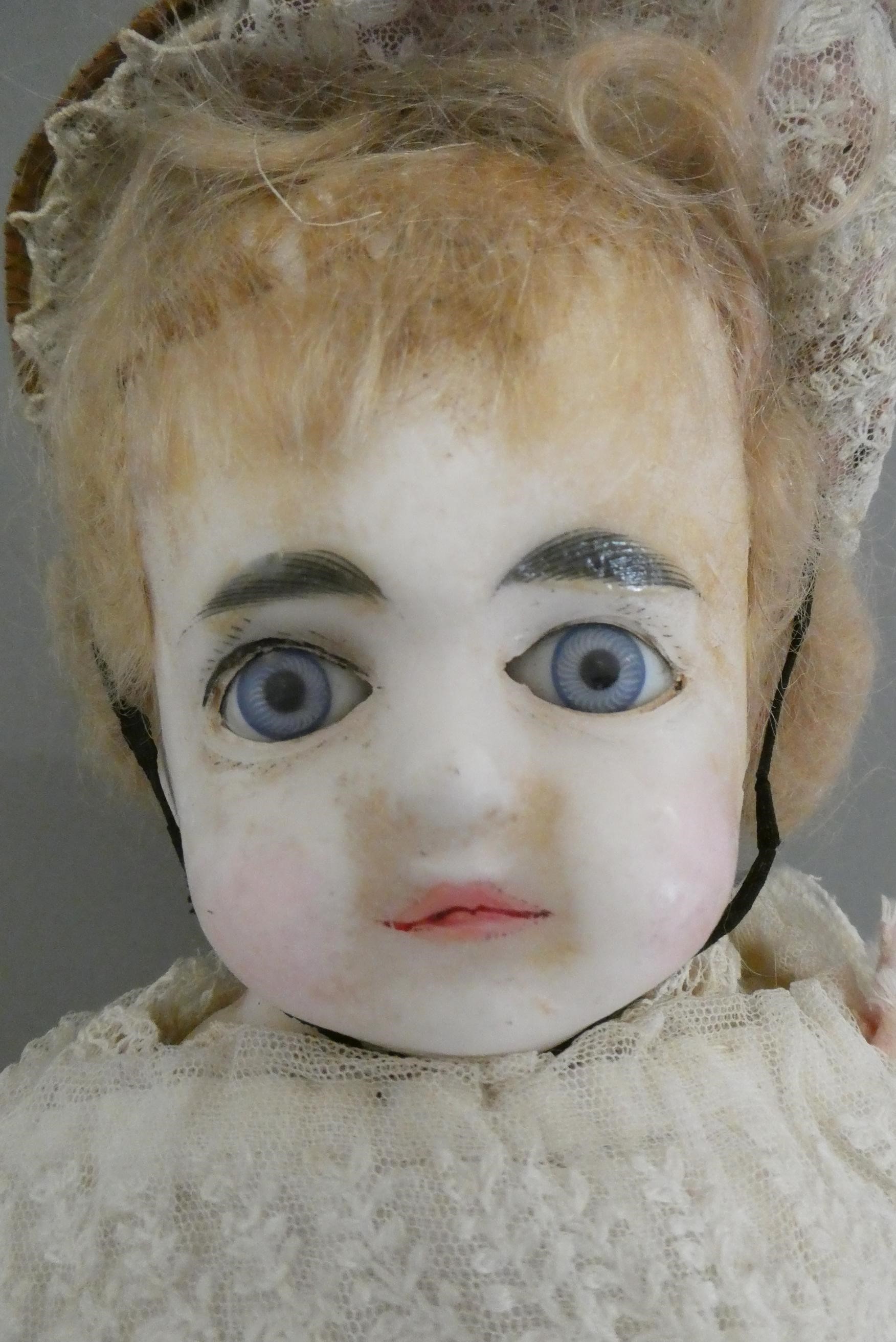 A Victorian wax shoulder head doll, with blue glass fixed eyes, closed mouth, composition lower Image