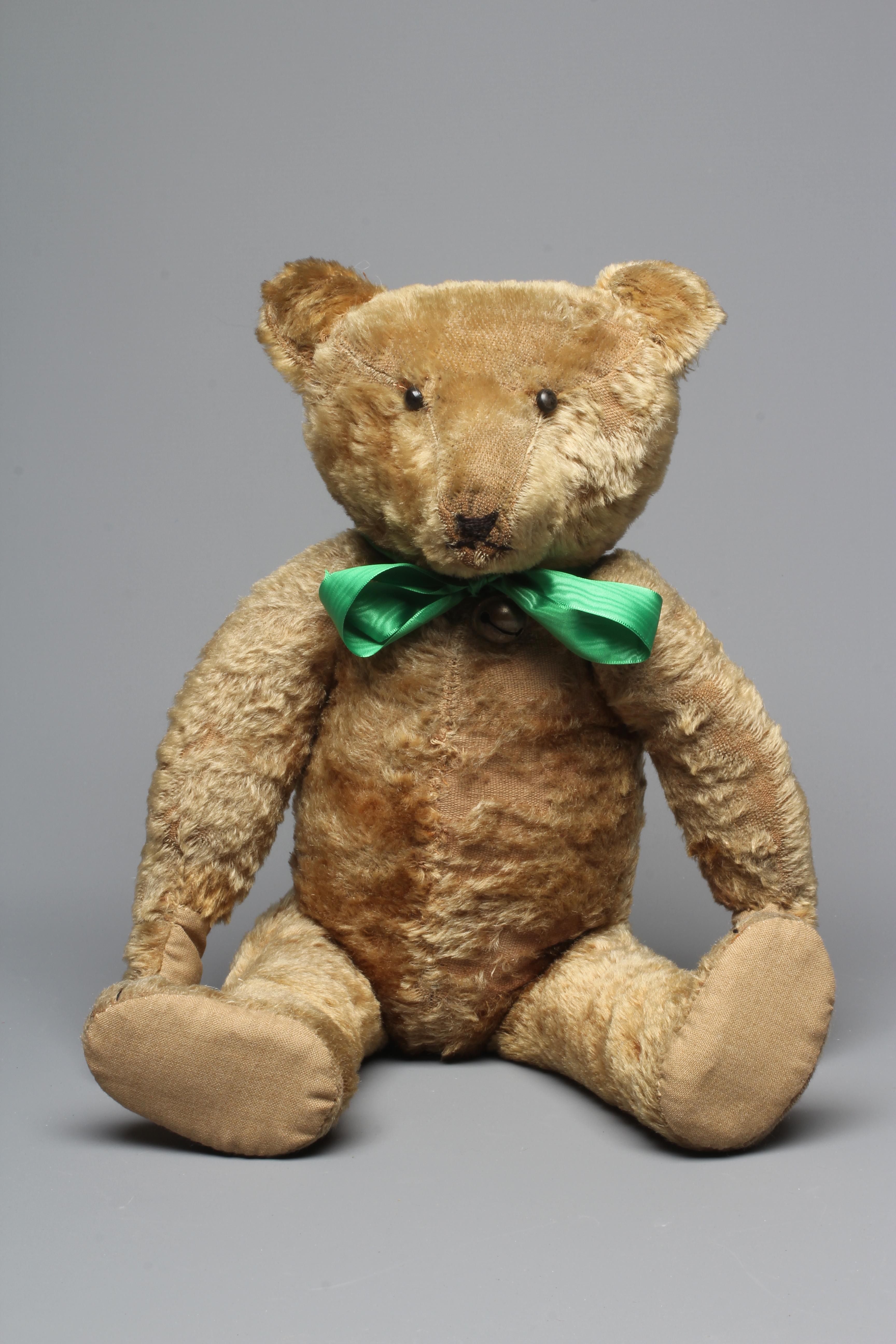 A pre-war shoe button eye teddy bear, with sewn nose, brown plush, bell to neck, jointed shoulders Image
