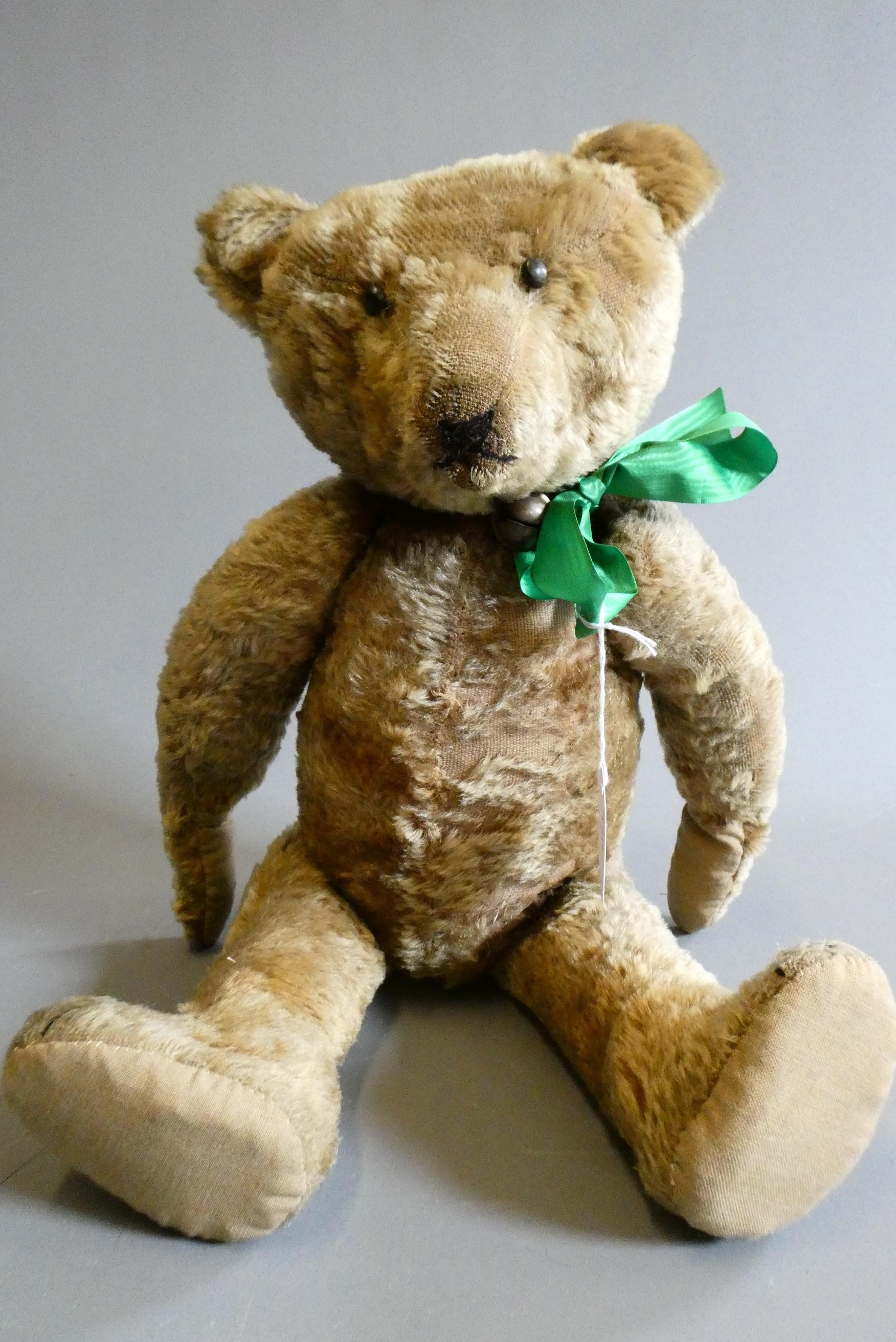 A pre-war shoe button eye teddy bear, with sewn nose, brown plush, bell to neck, jointed shoulders Image