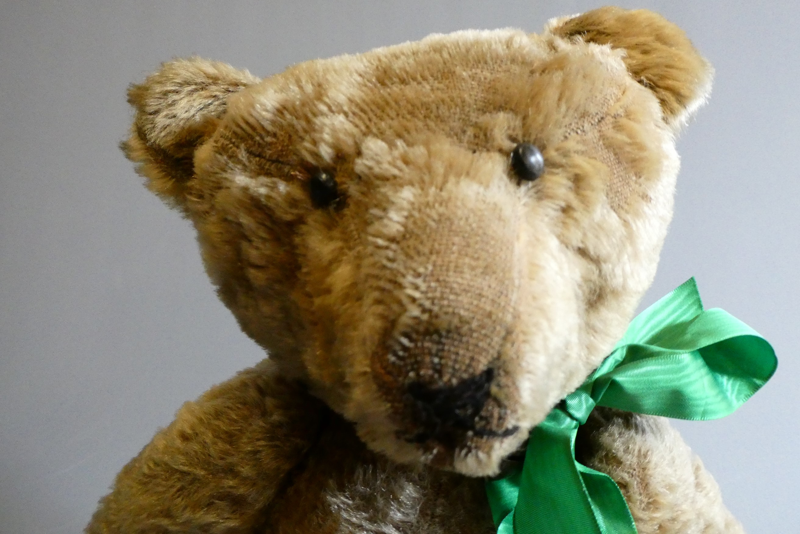 A pre-war shoe button eye teddy bear, with sewn nose, brown plush, bell to neck, jointed shoulders Image