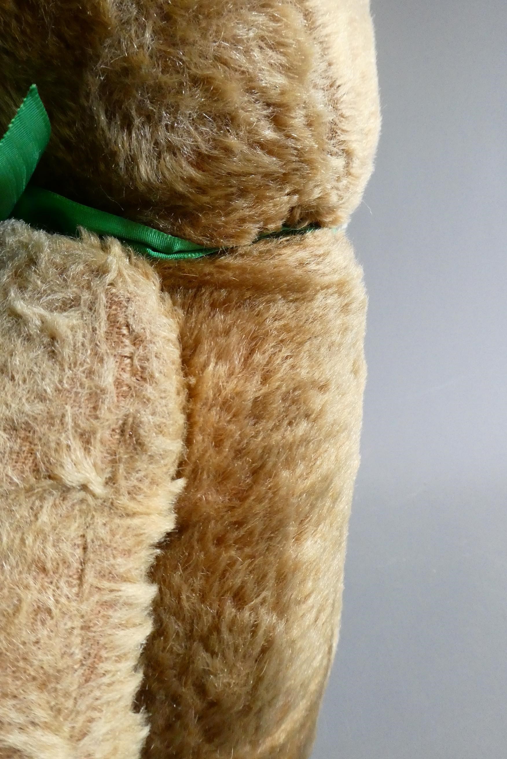 A pre-war shoe button eye teddy bear, with sewn nose, brown plush, bell to neck, jointed shoulders Image