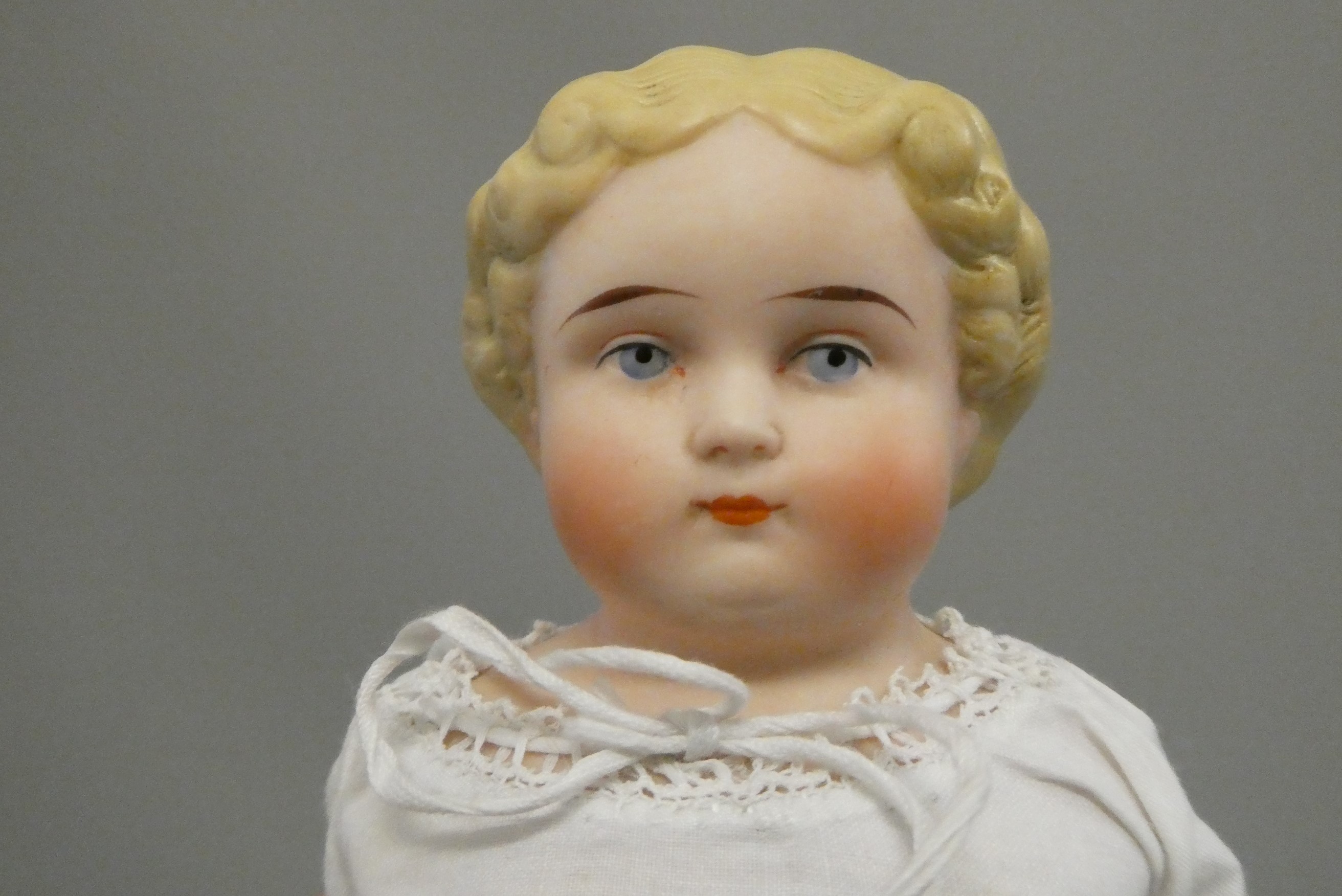 An antique bisque shoulder head doll, with moulded hair, painted features, bisque lower limbs and Image