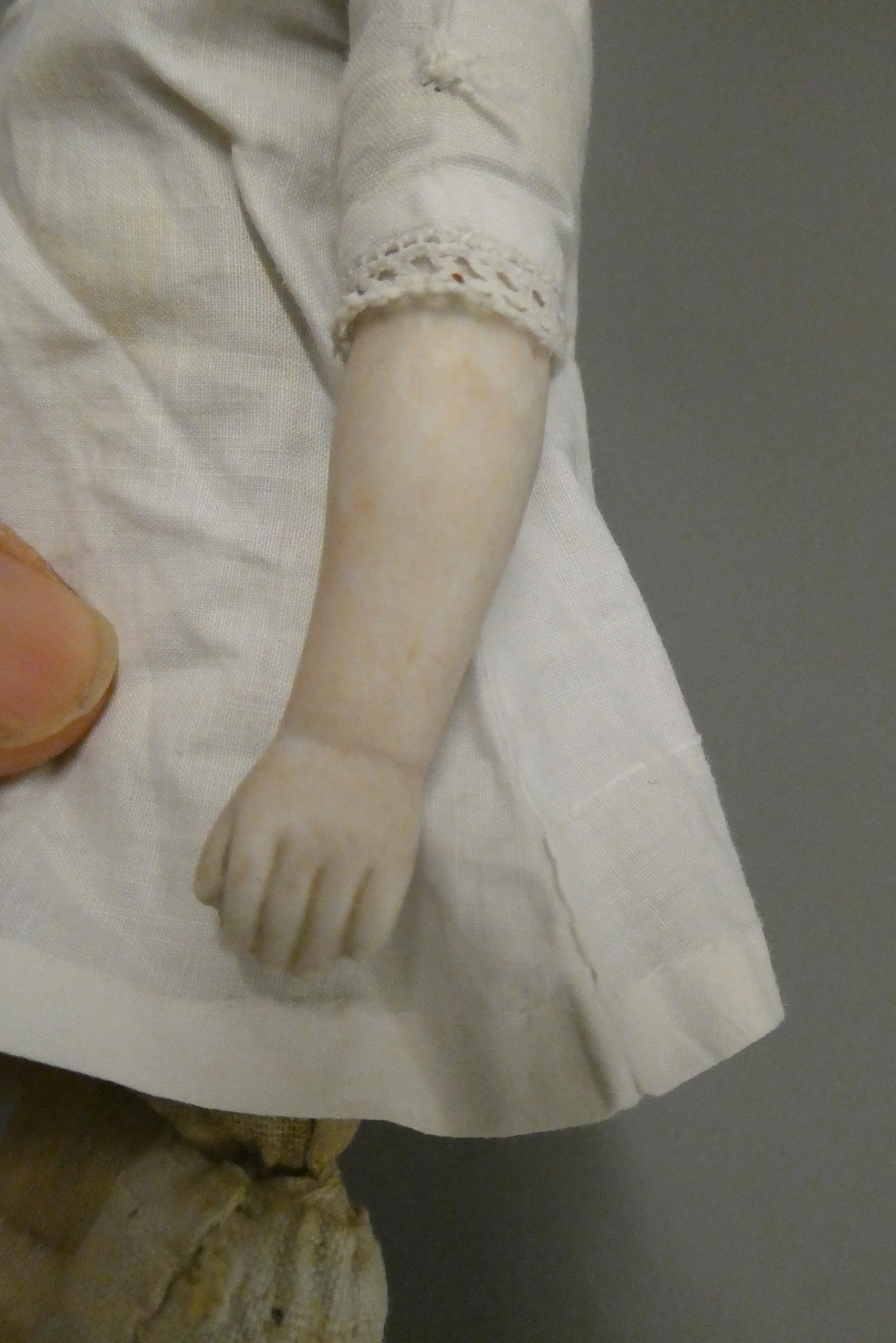 An antique bisque shoulder head doll, with moulded hair, painted features, bisque lower limbs and Image