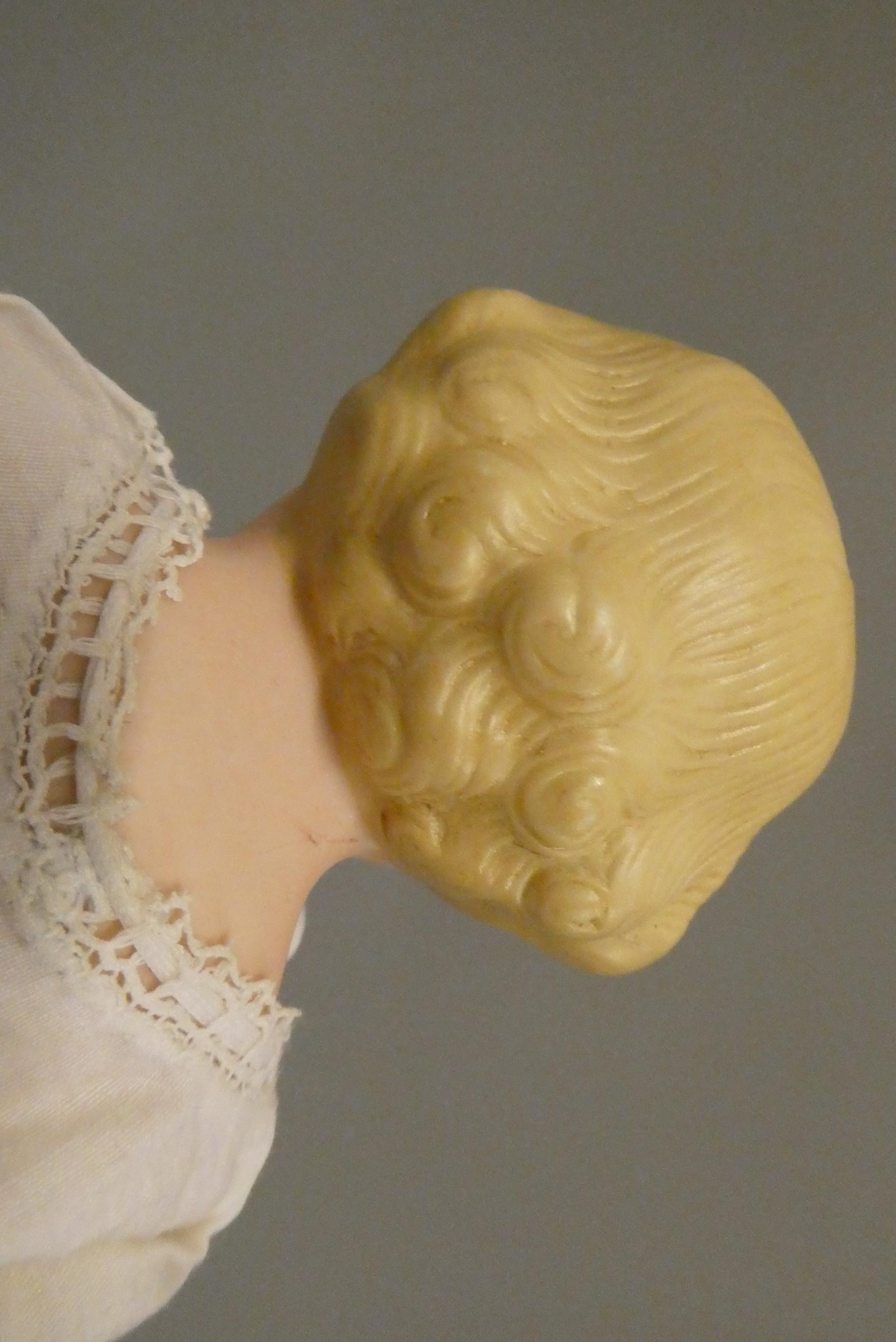 An antique bisque shoulder head doll, with moulded hair, painted features, bisque lower limbs and Image