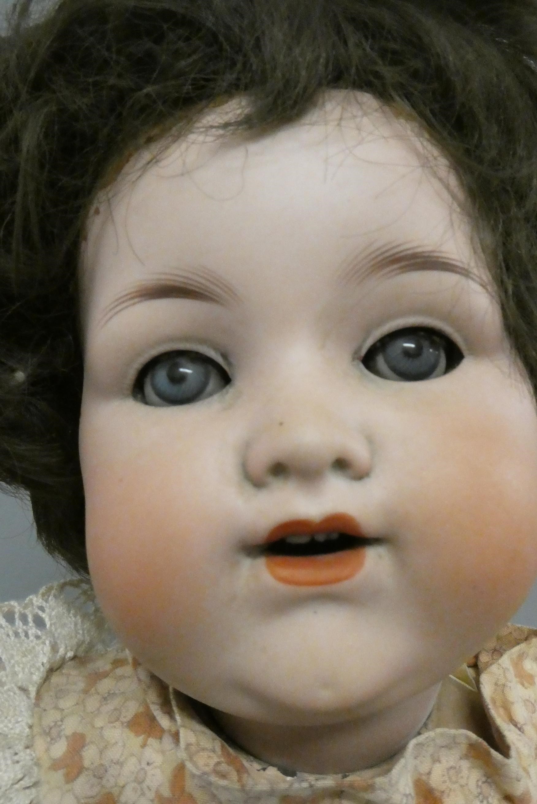 An Armand Marseille bisque socket head doll, with blue glass sleeping eyes, open mouth, teeth, bent Image