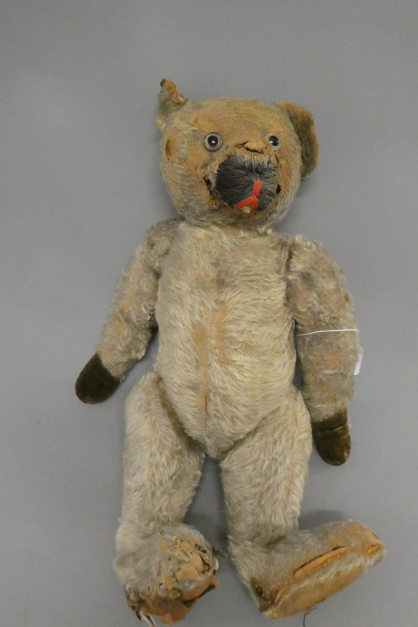 A pre-war teddy bear, with clear glass eyes, straw filling and hump back, 18" long (Est. plus 24% Image