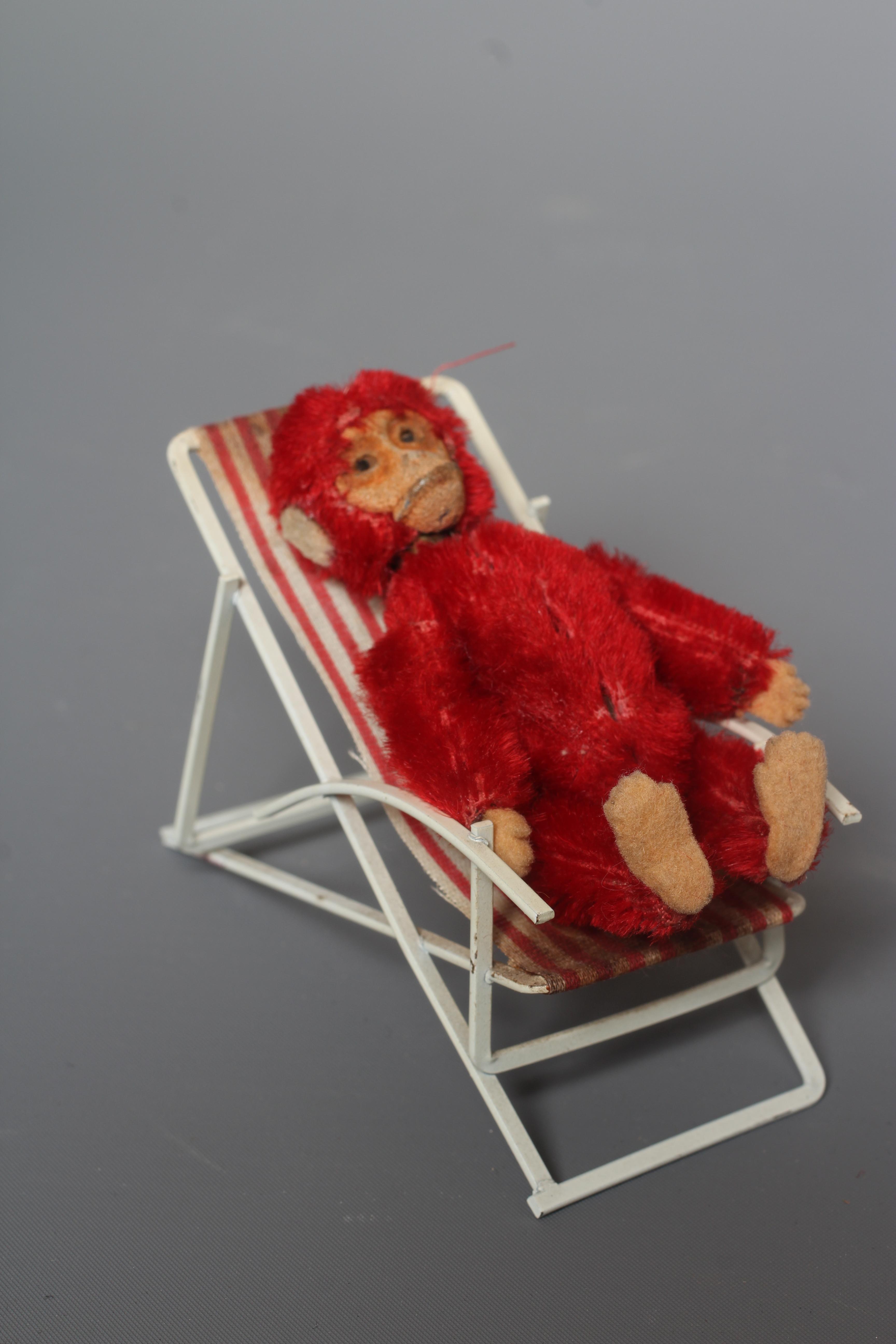 A rare Schuco red monkey compact, with felt hands and feet, powder puff and associated deckchair, Image