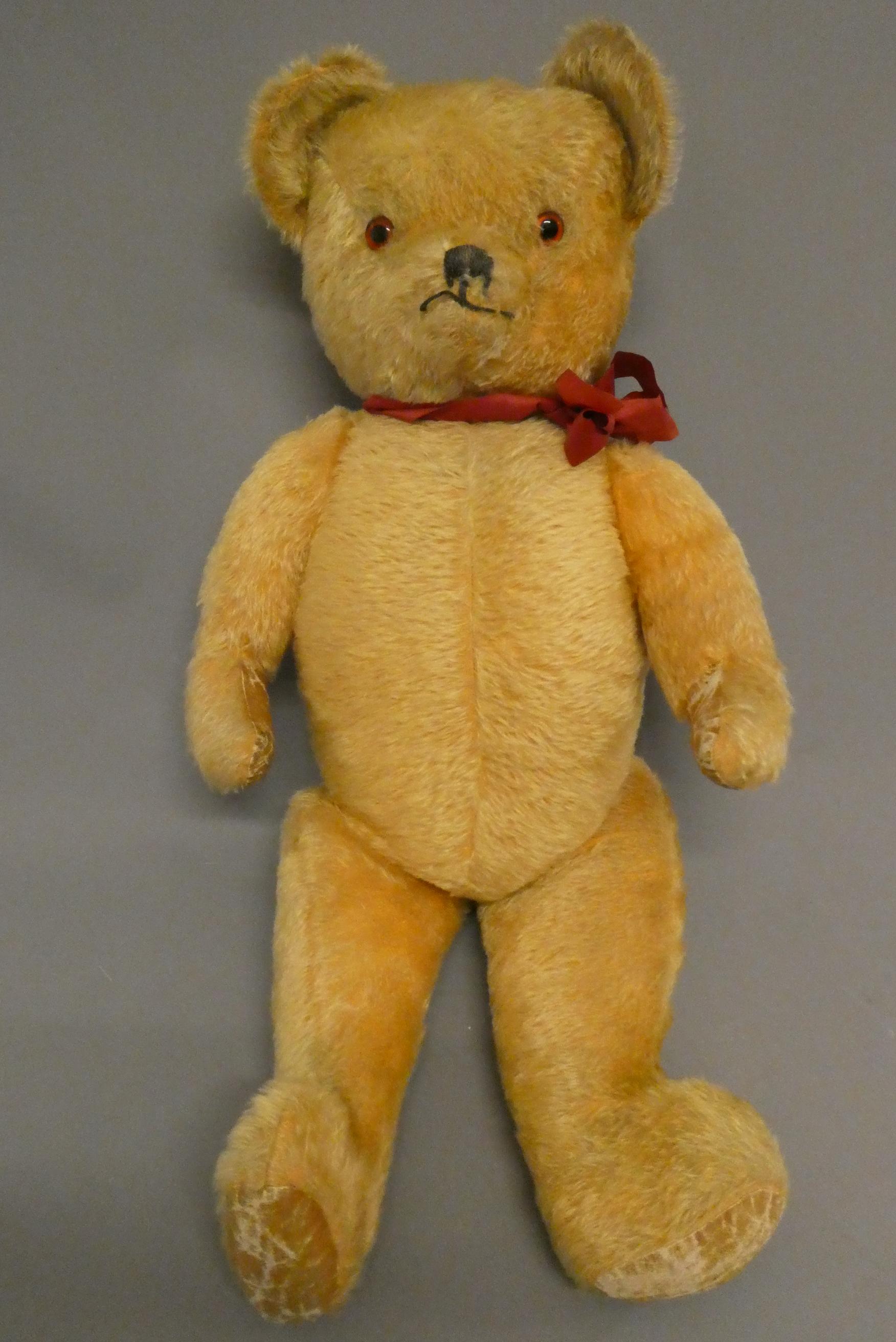 A 1950s orange plush teddy bear, with sewn nose and mouth, amber glass eyes and fabric pads, 30" Image