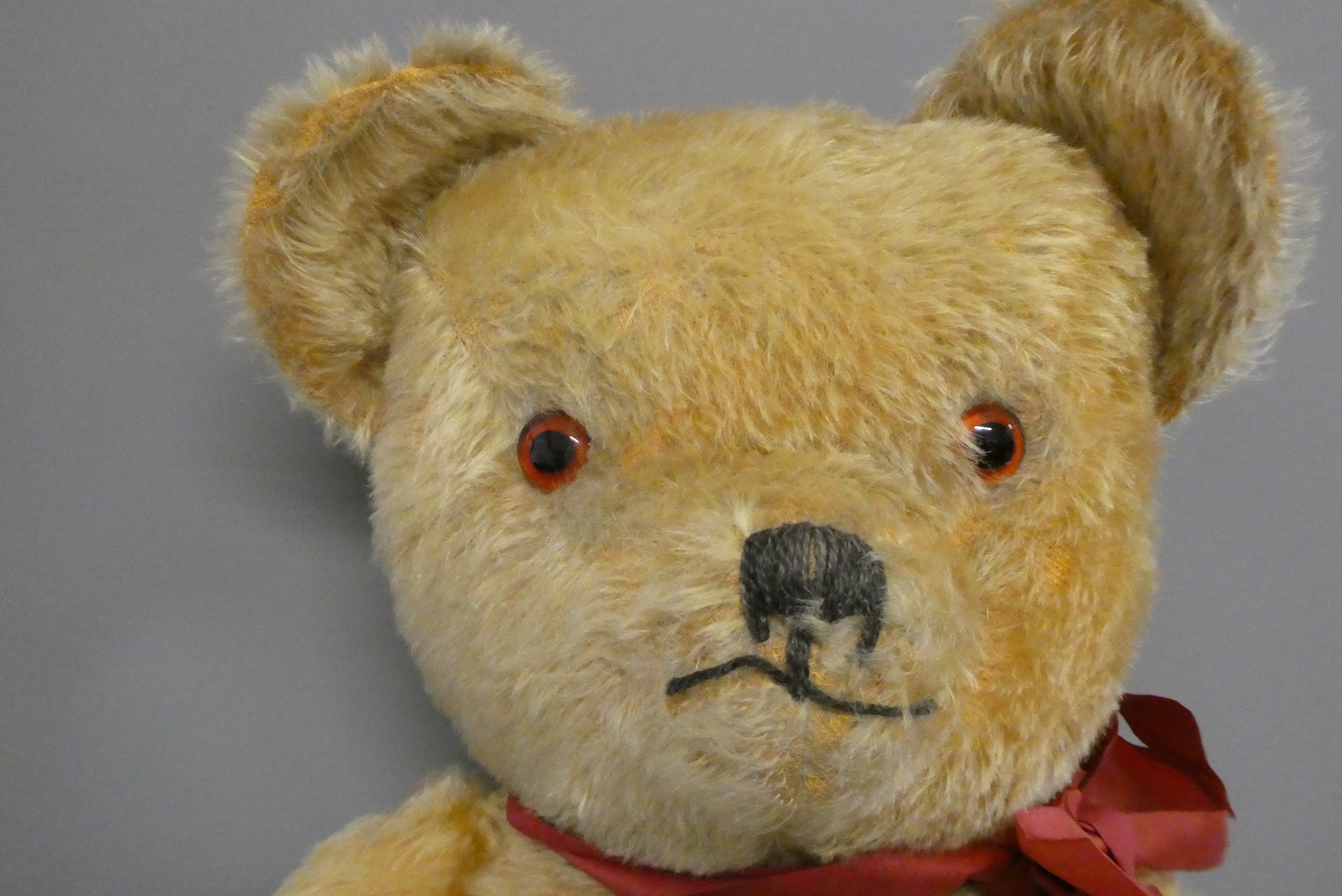 A 1950s orange plush teddy bear, with sewn nose and mouth, amber glass eyes and fabric pads, 30" Image