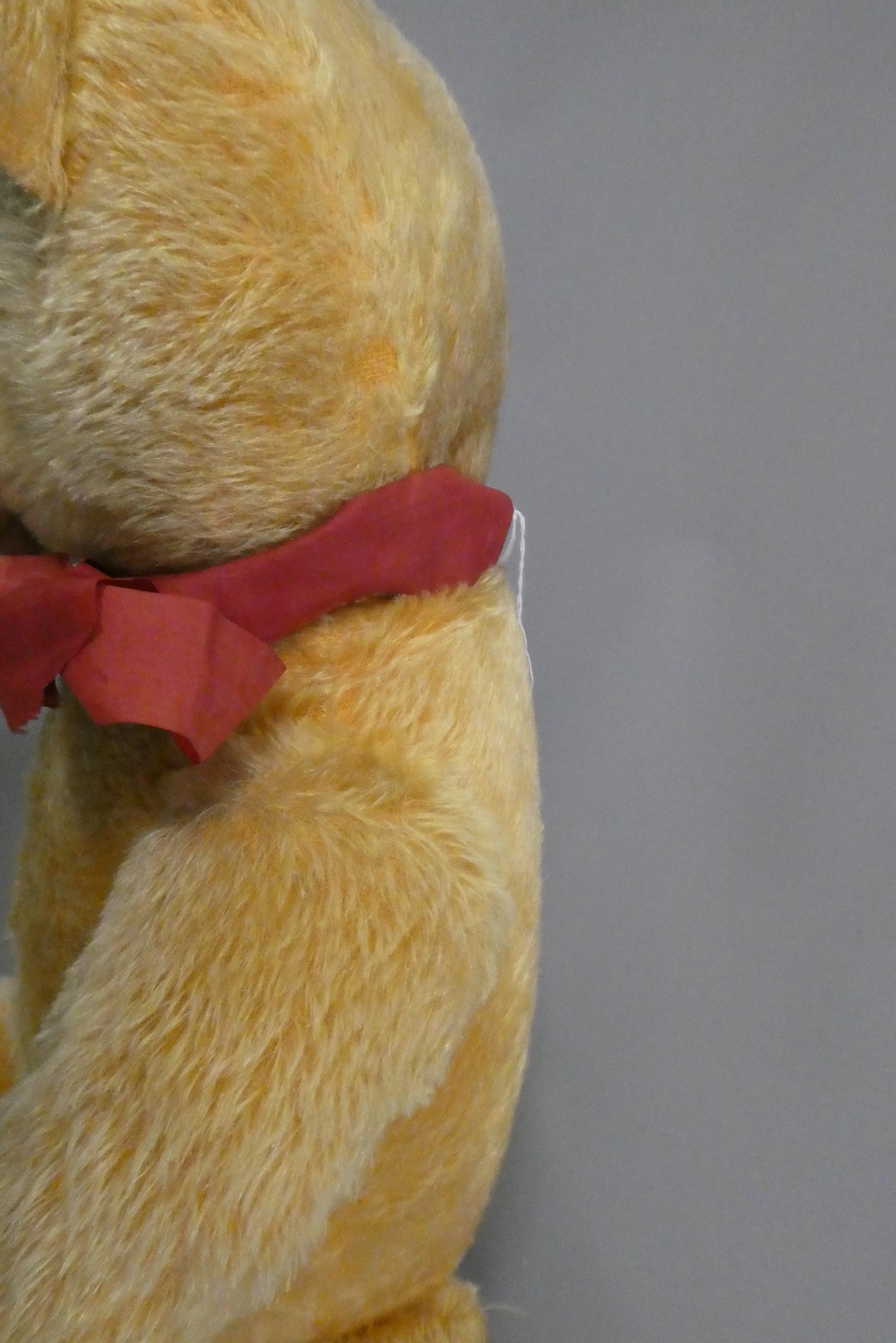 A 1950s orange plush teddy bear, with sewn nose and mouth, amber glass eyes and fabric pads, 30" Image