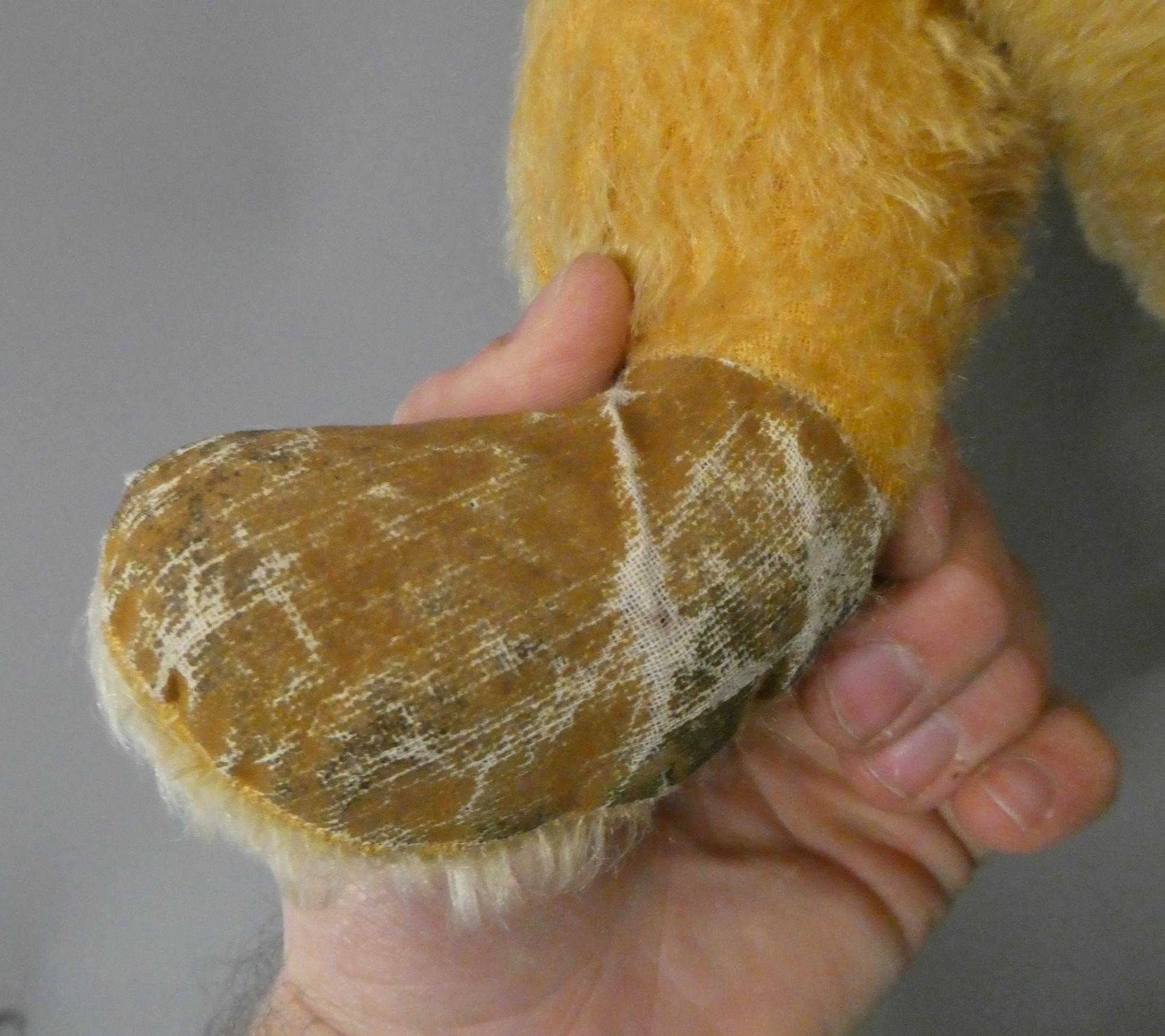 A 1950s orange plush teddy bear, with sewn nose and mouth, amber glass eyes and fabric pads, 30" Image