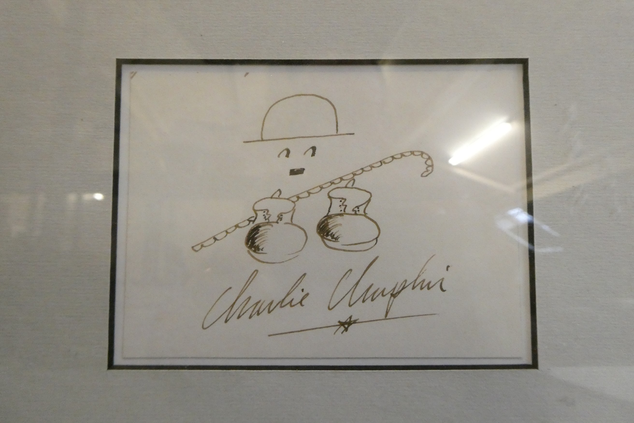 Charlie Chaplin autograph, together with small ink illustration and framed with a photograph, 12 Image
