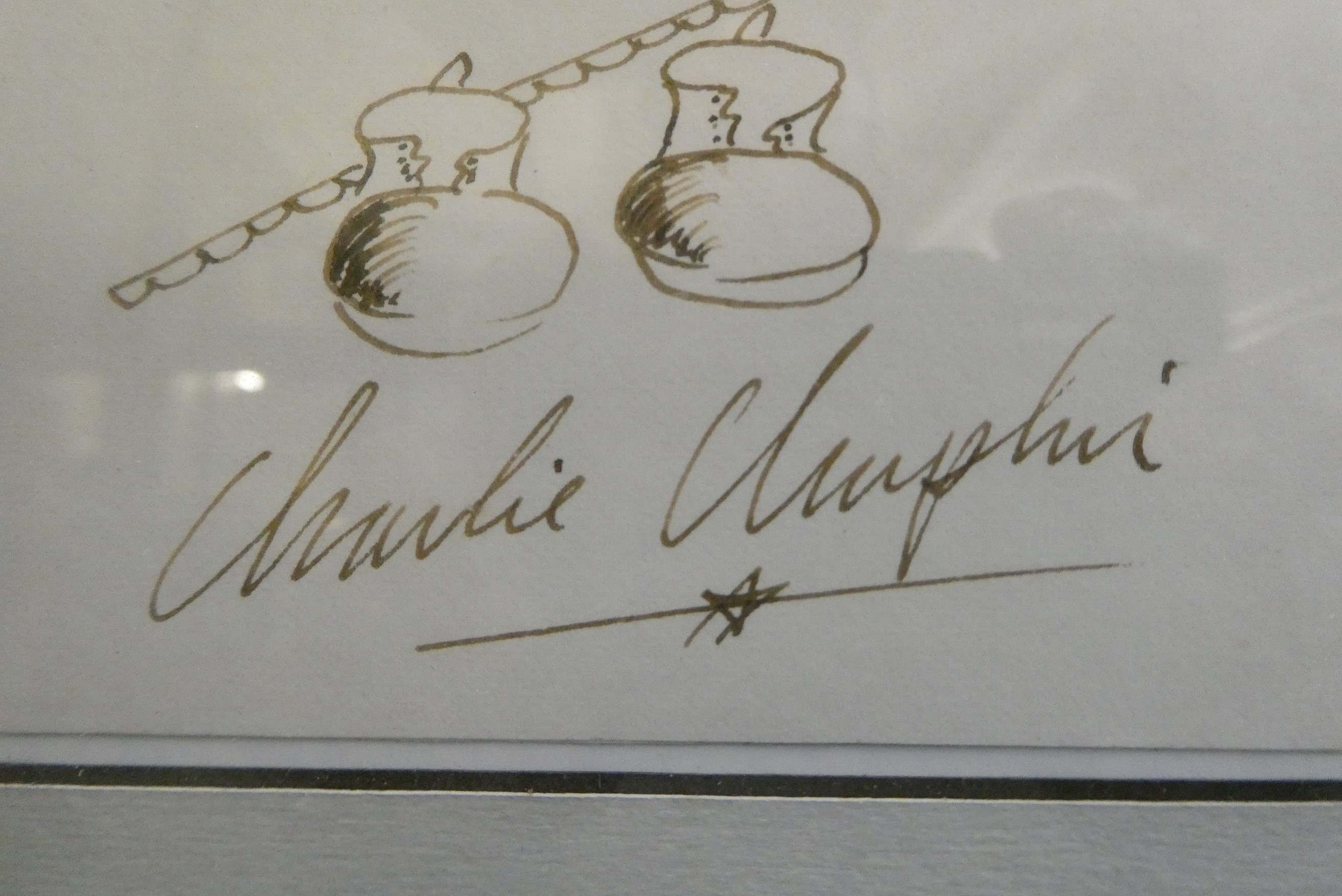 Charlie Chaplin autograph, together with small ink illustration and framed with a photograph, 12 Image