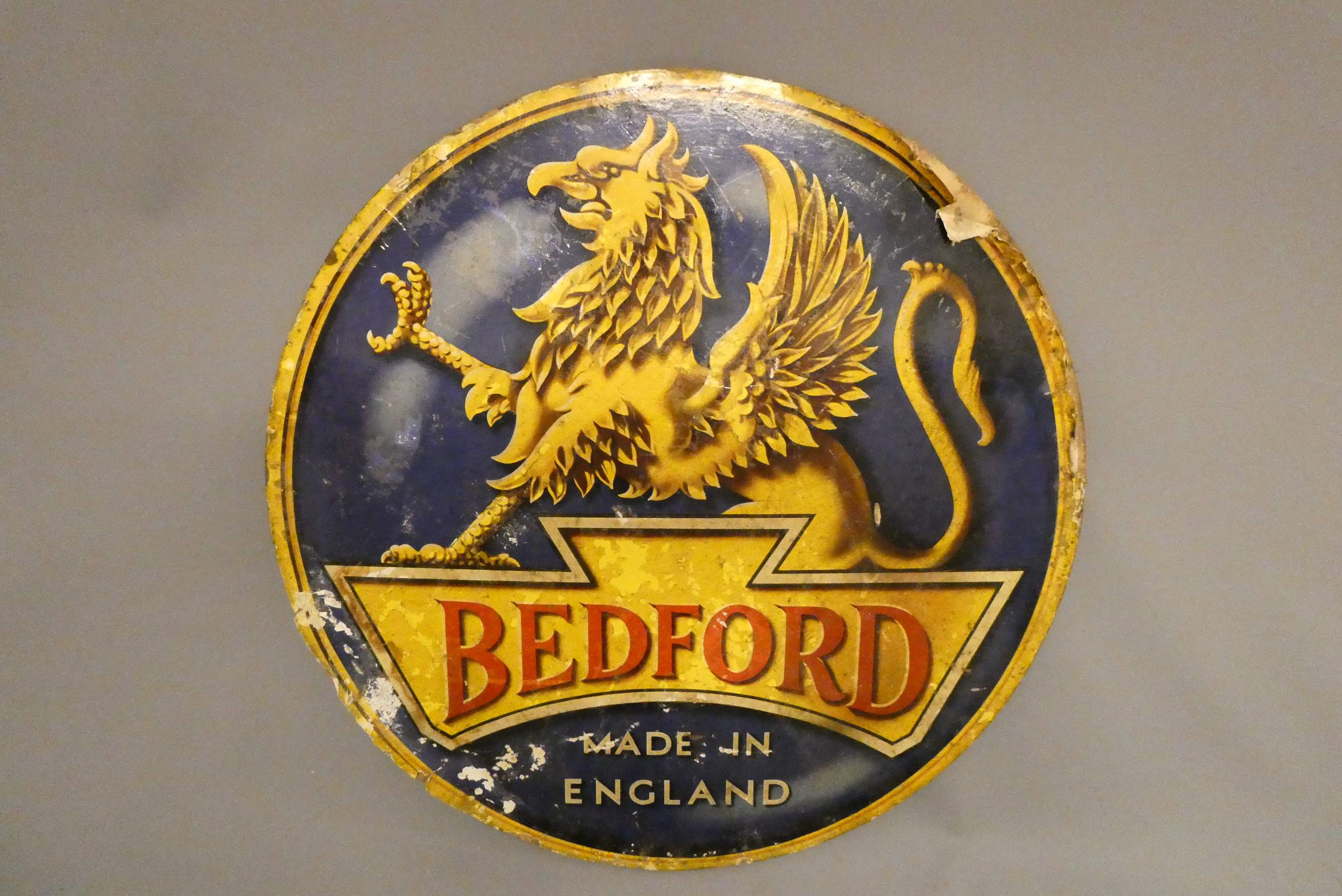 A large circular Bedford Garage sign comprising a colour paper print glued to wooden back board Image