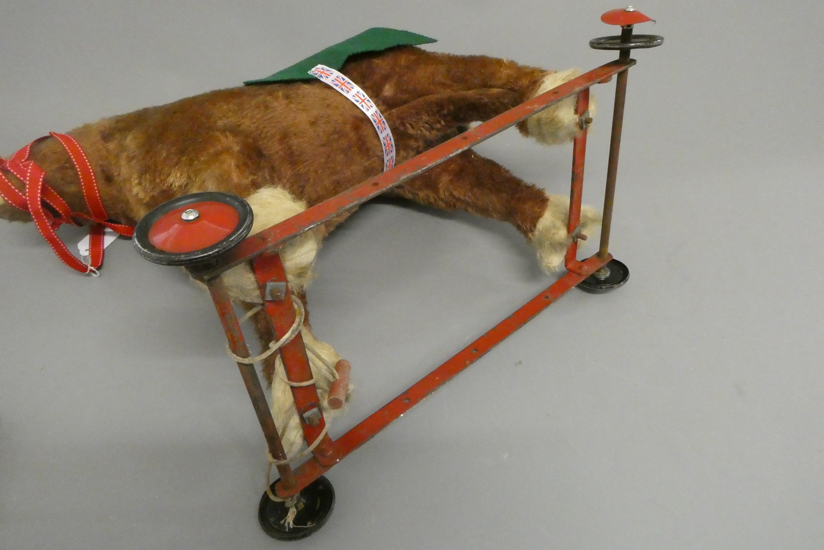 A vintage plush pull-a-long horse, with clear glass eyes and red metal frame with four wheels, 20" x Image