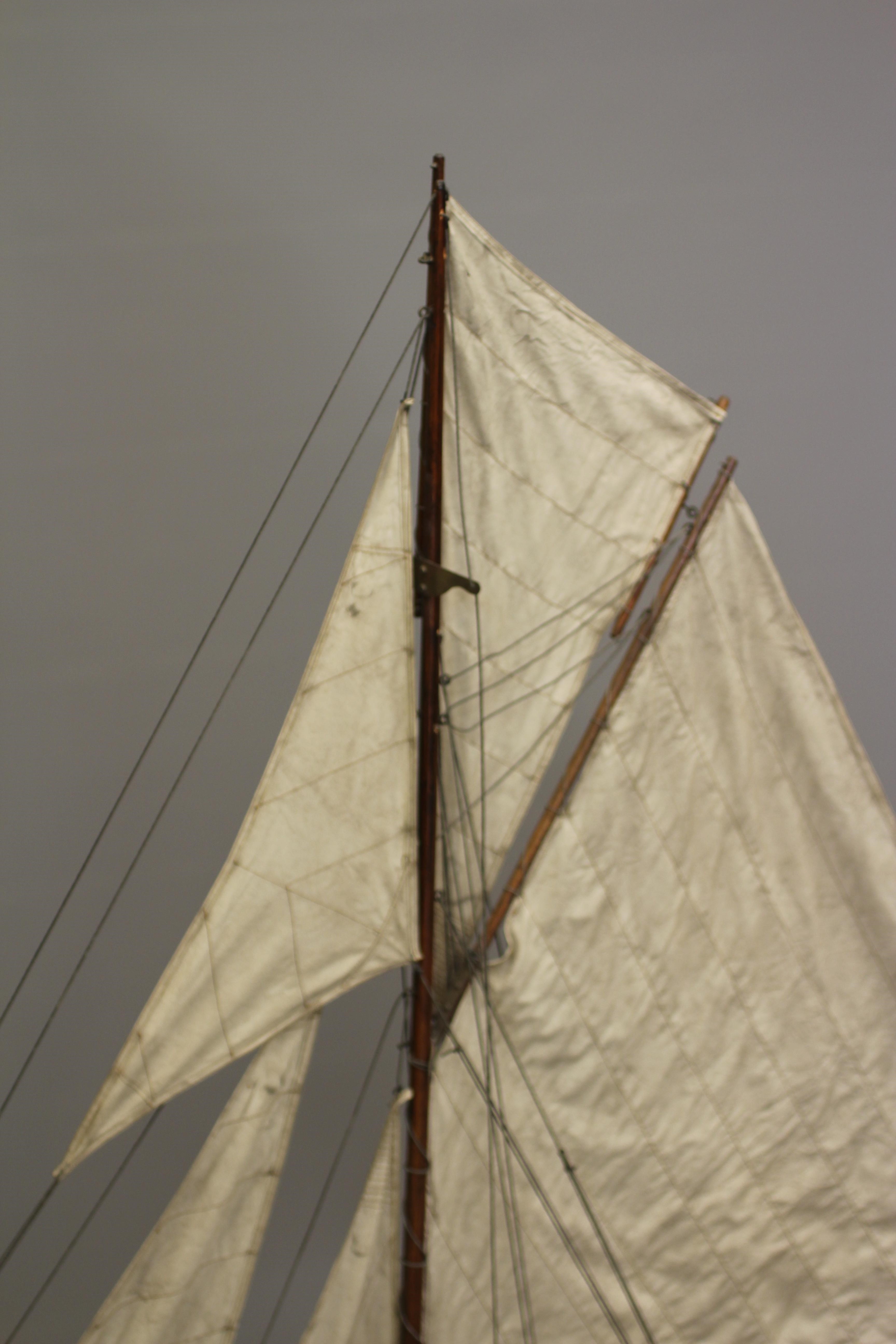 A wooden yacht model fitted with main sail Image