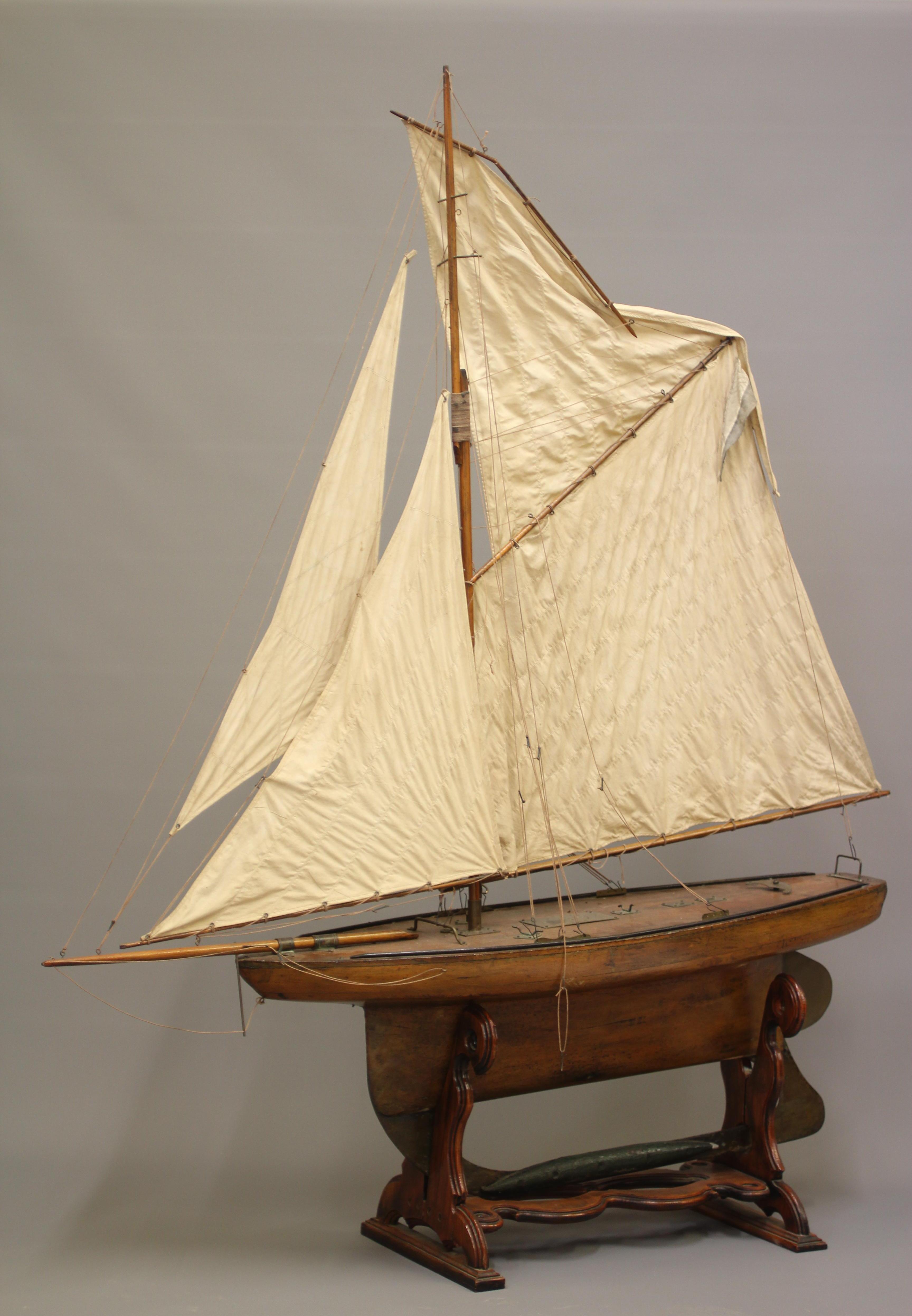 A large wooden yacht model fitted with main sail Image