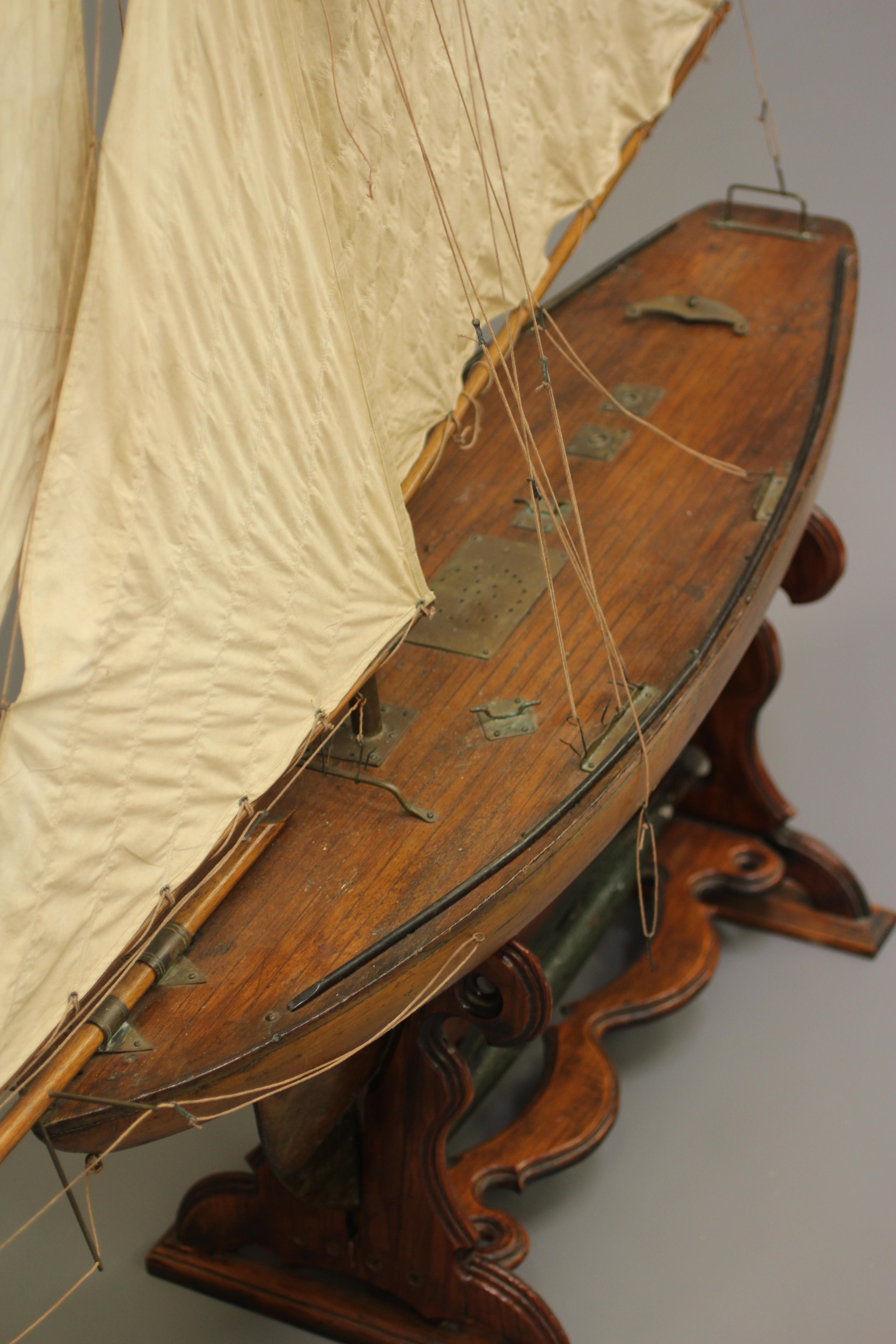 A large wooden yacht model fitted with main sail Image