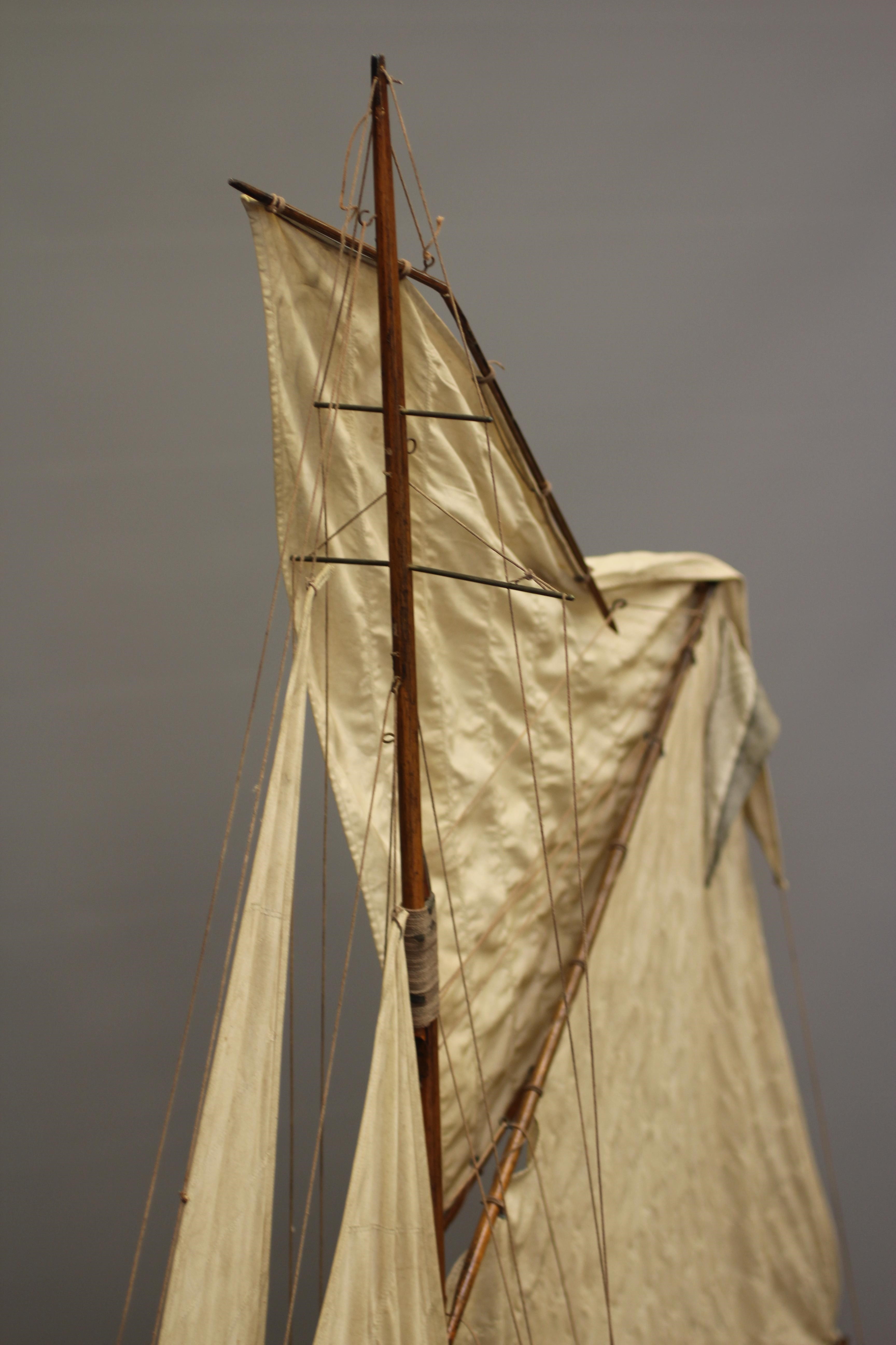 A large wooden yacht model fitted with main sail Image