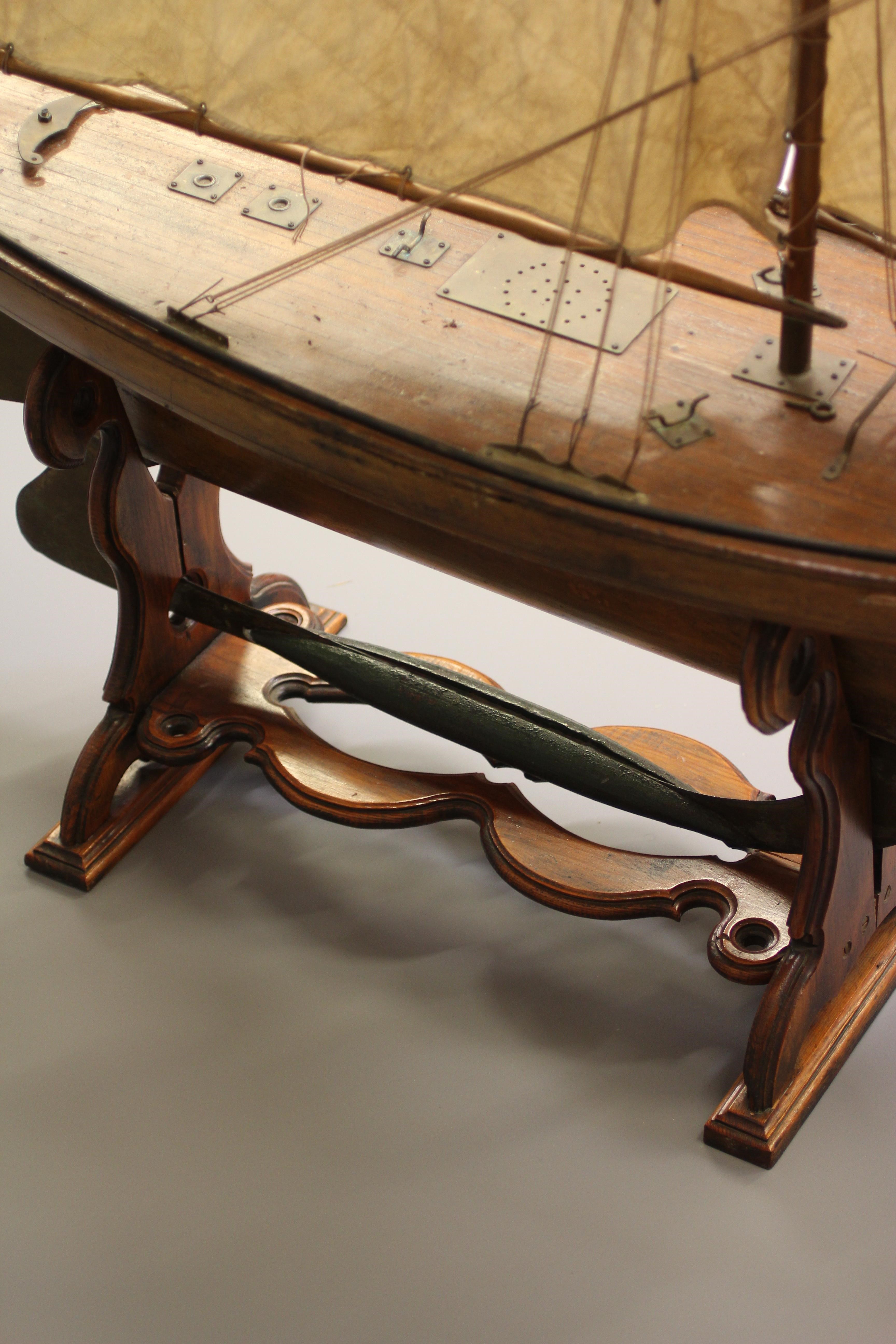 A large wooden yacht model fitted with main sail Image