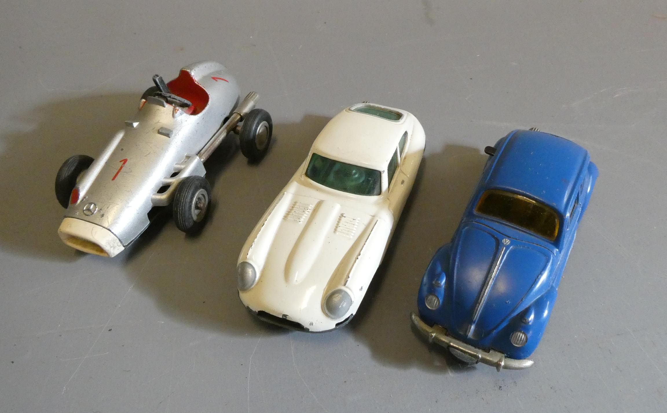 Three Schuco clockwork Micro Racers comprising VW Beetle, Silver F1 race car and E Type Jaguar, some Image