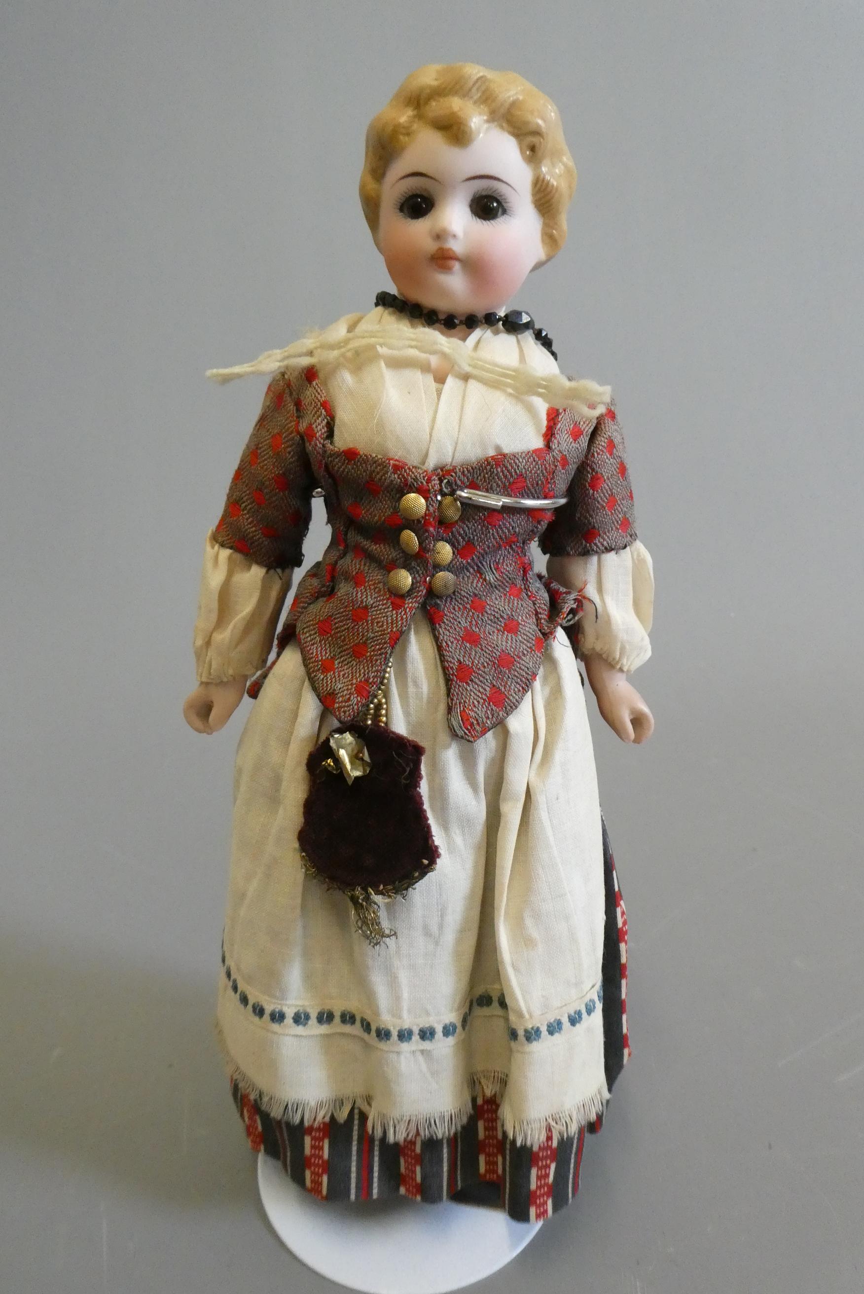 A bisque shoulder head doll, with brown glass fixed eyes, closed mouth, moulded blond hair, fabric Image
