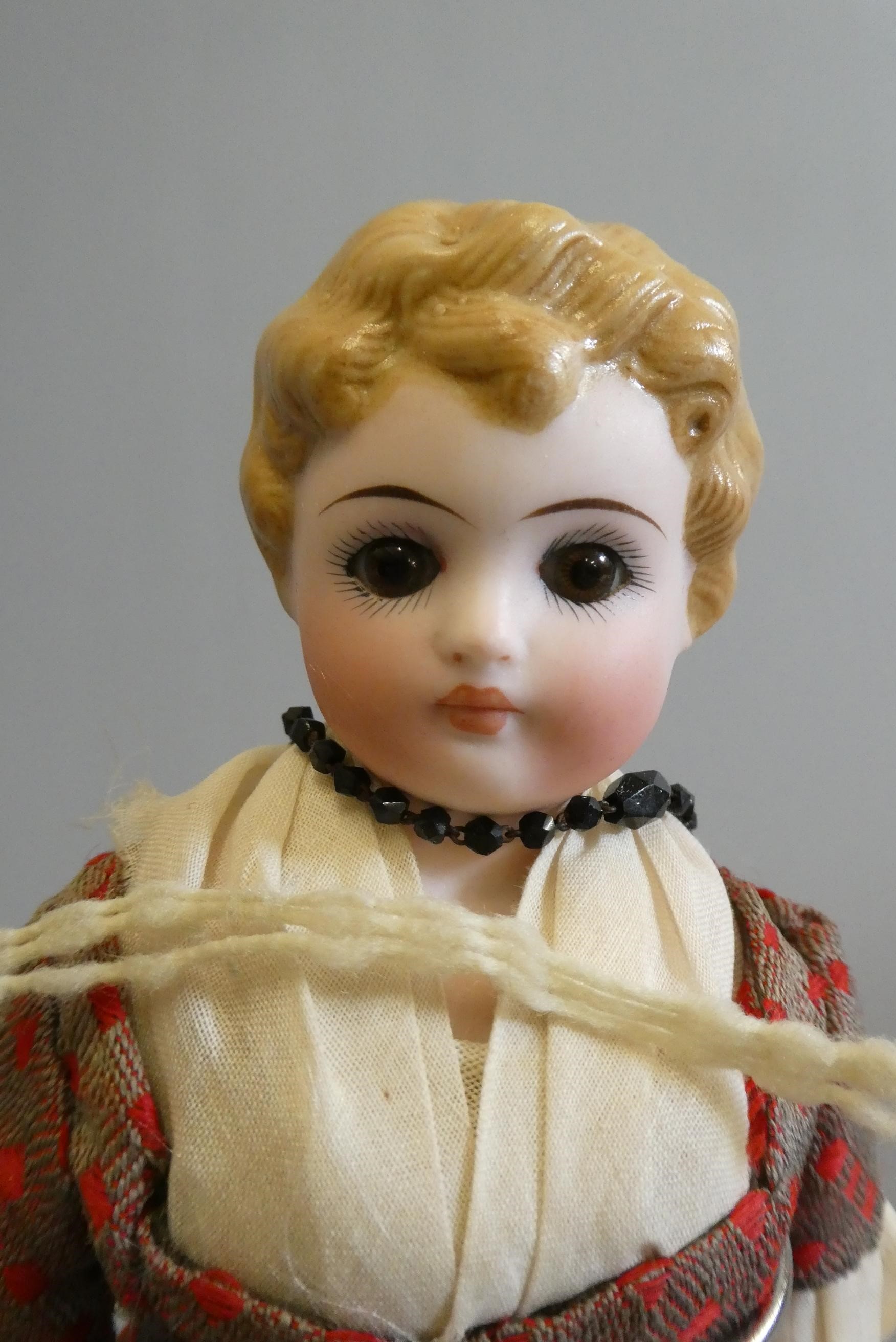 A bisque shoulder head doll, with brown glass fixed eyes, closed mouth, moulded blond hair, fabric Image