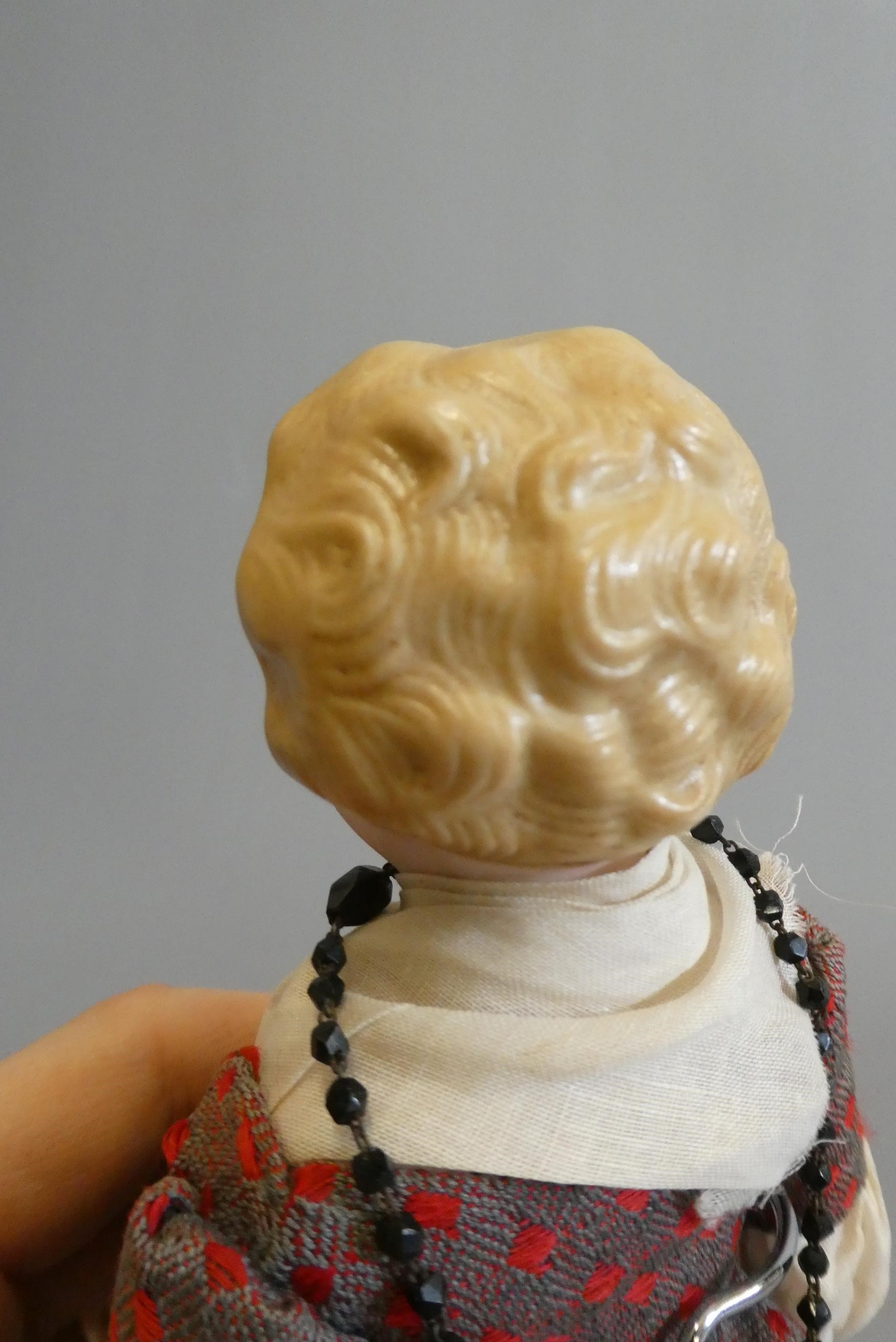 A bisque shoulder head doll, with brown glass fixed eyes, closed mouth, moulded blond hair, fabric Image