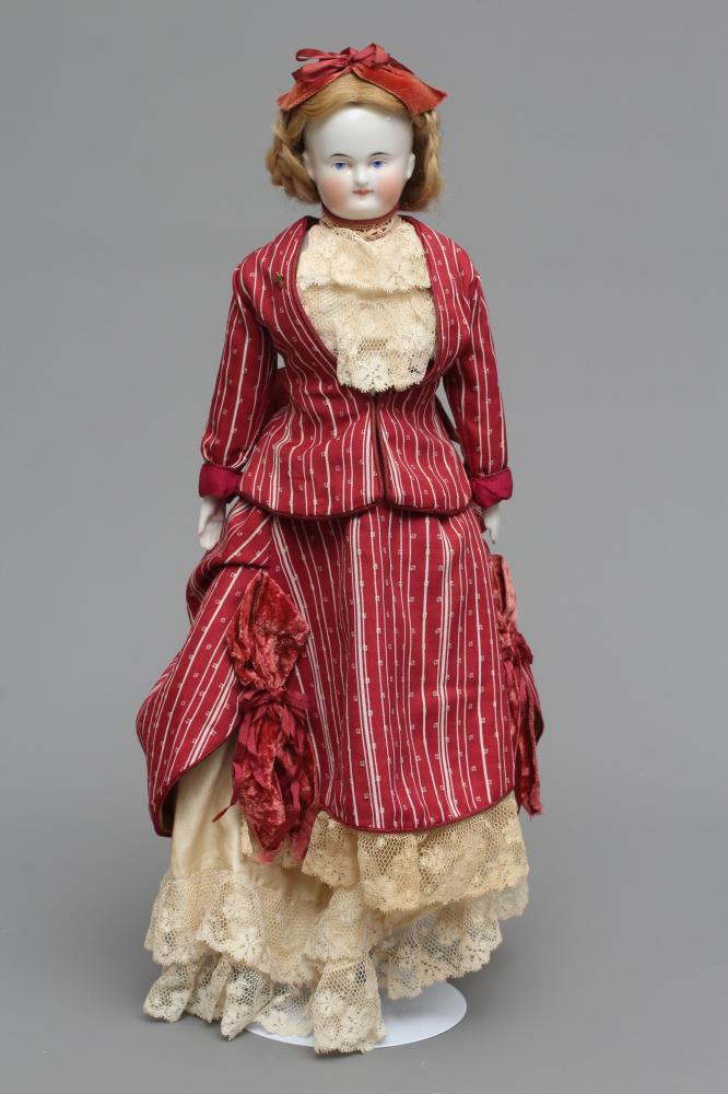 A Victorian china shoulder head doll, with painted face, blond wig, fabric body, china lower limbs Image