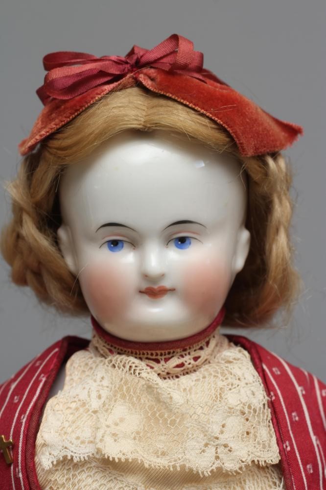 A Victorian china shoulder head doll, with painted face, blond wig, fabric body, china lower limbs Image