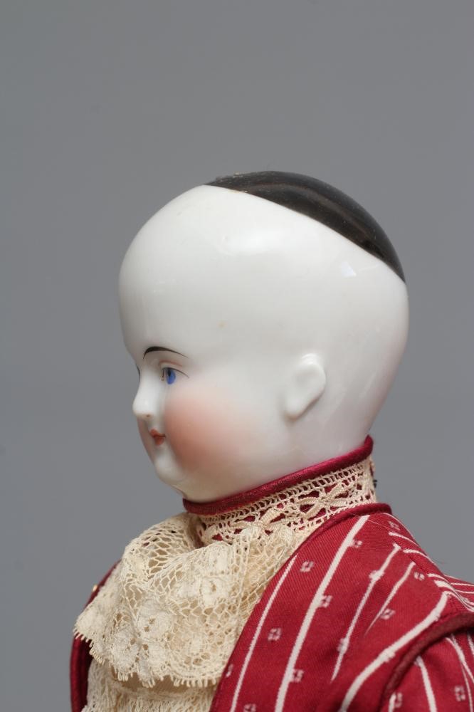A Victorian china shoulder head doll, with painted face, blond wig, fabric body, china lower limbs Image