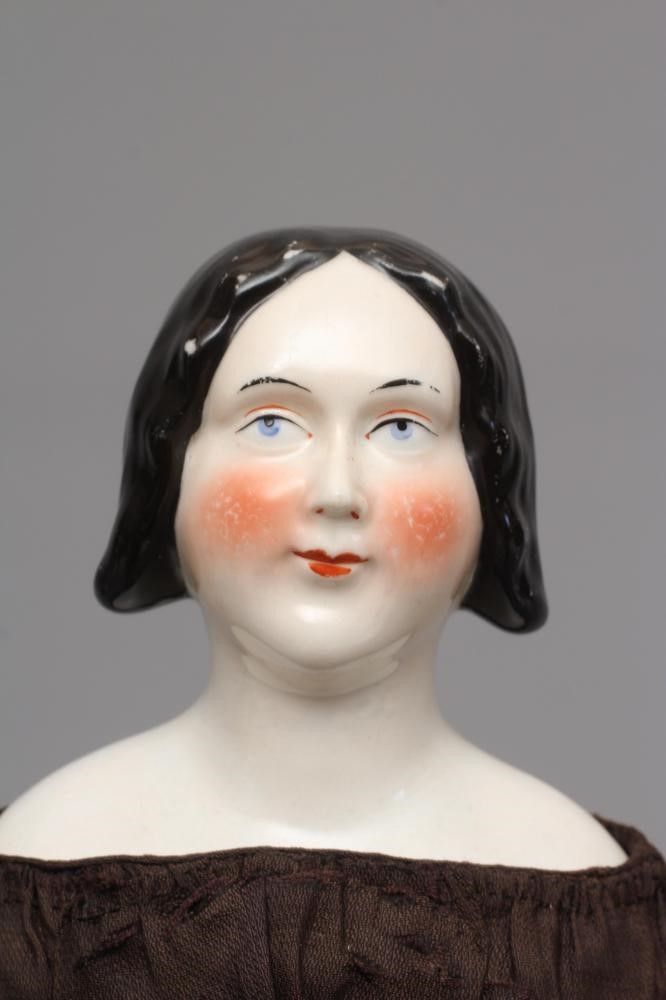A Victorian china shoulder head doll, with painted face, well moulded hair, fabric body, kid lower Image