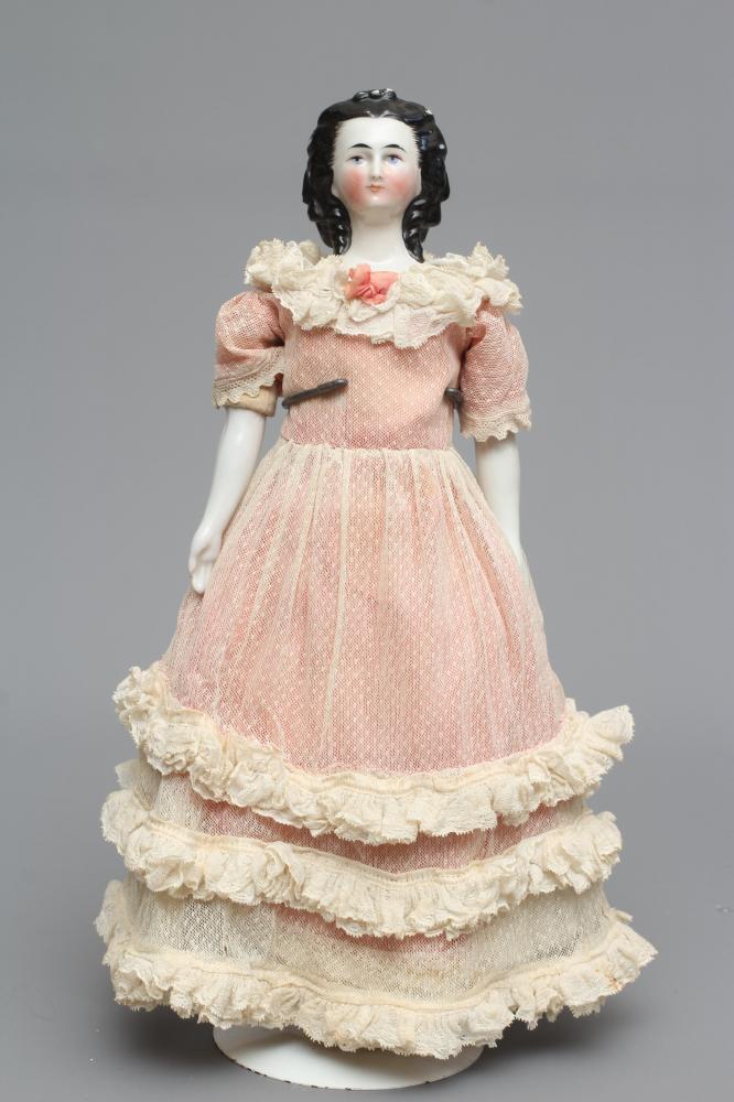 A Victorian china shoulder head doll, with painted face, moulded netted hair, fabric body, china Image