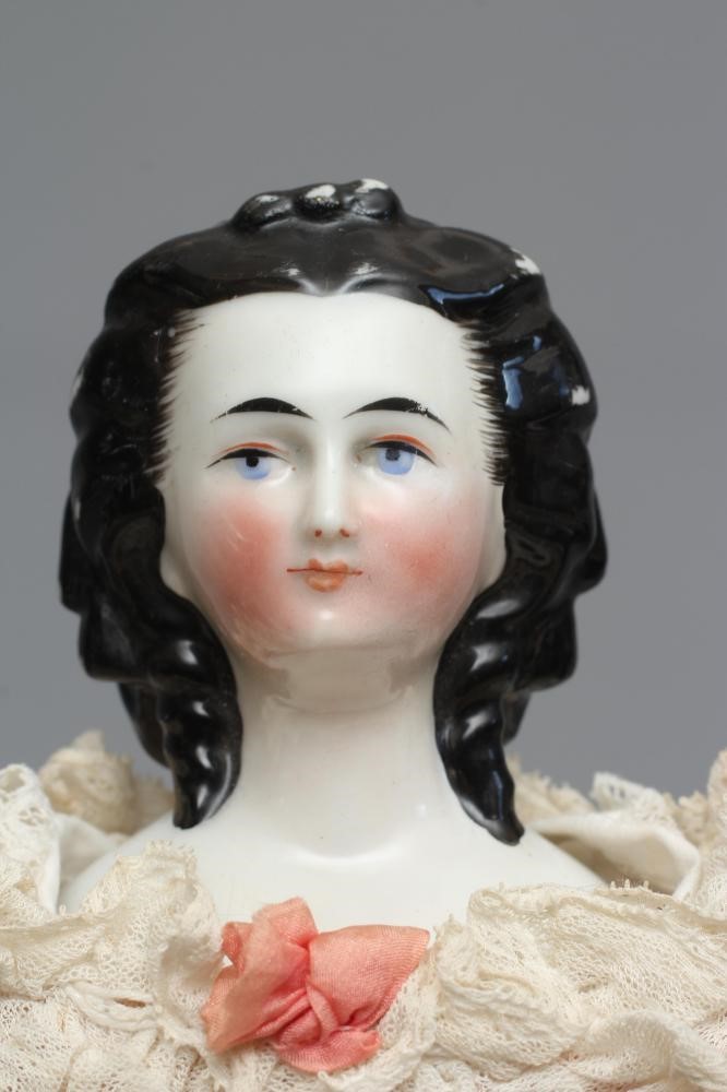 A Victorian china shoulder head doll, with painted face, moulded netted hair, fabric body, china Image