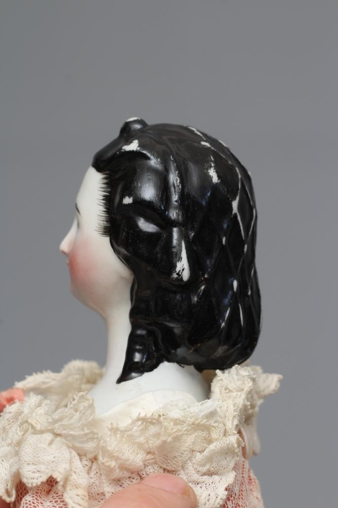 A Victorian china shoulder head doll, with painted face, moulded netted hair, fabric body, china Image