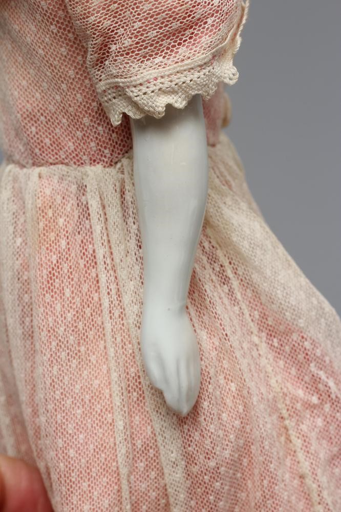 A Victorian china shoulder head doll, with painted face, moulded netted hair, fabric body, china Image