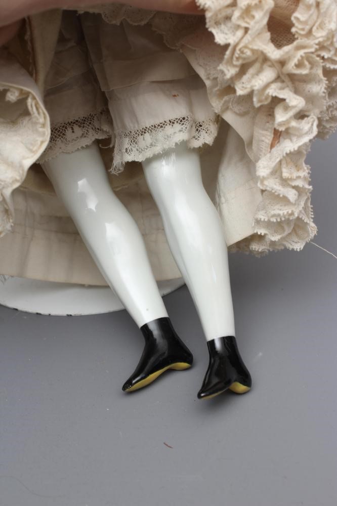 A Victorian china shoulder head doll, with painted face, moulded netted hair, fabric body, china Image