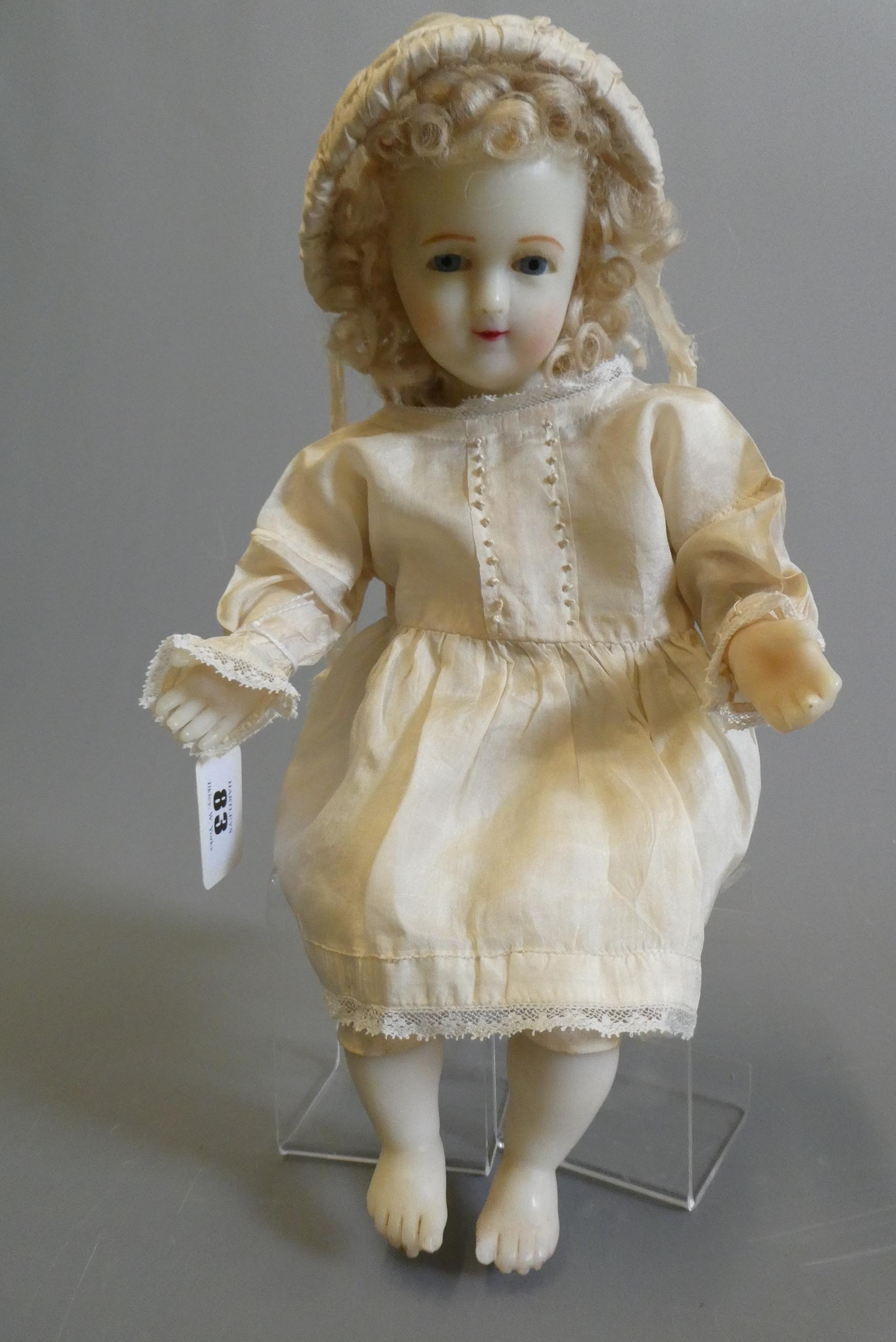 A seated wax shoulder head doll, with blue glass fixed eyes, open mouth, teeth, blond wig, fabric Image