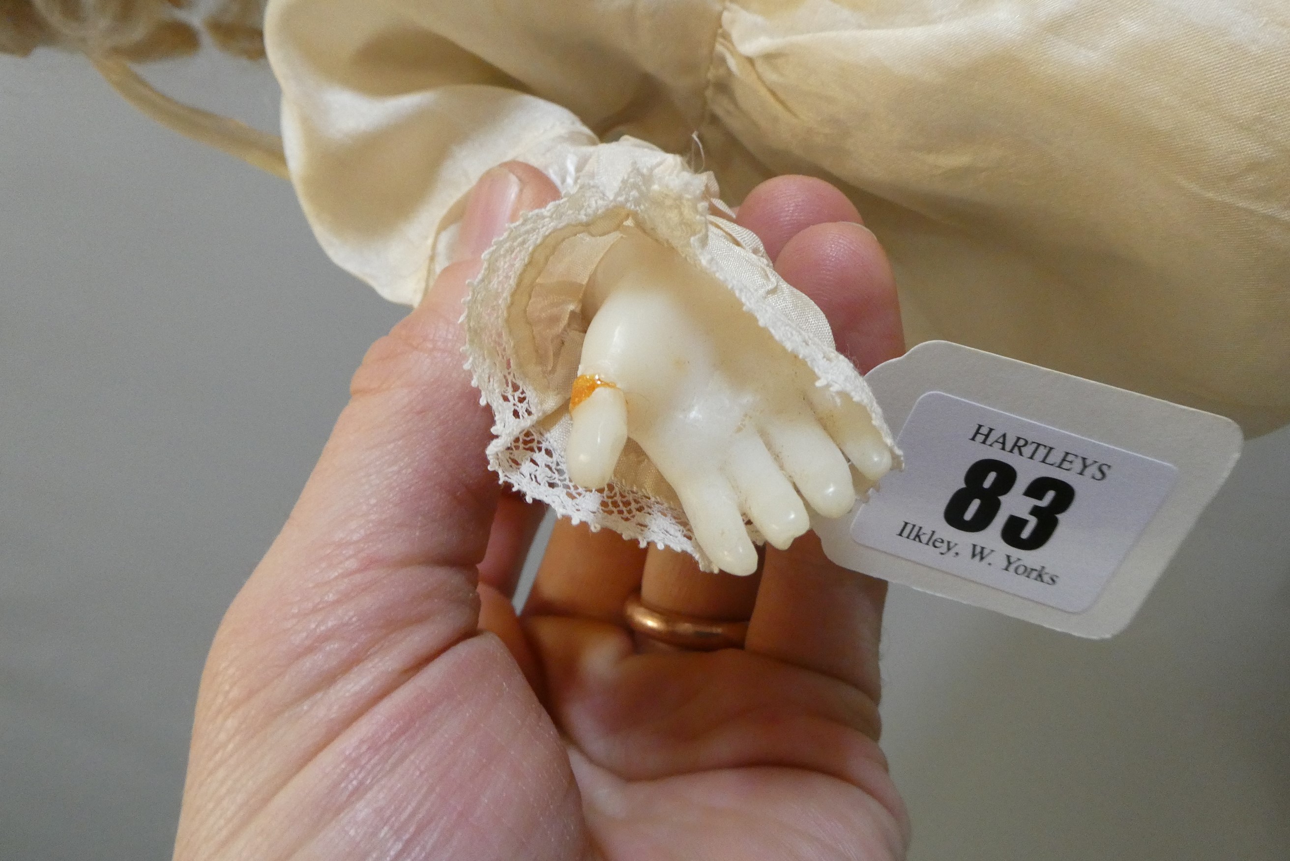 A seated wax shoulder head doll, with blue glass fixed eyes, open mouth, teeth, blond wig, fabric Image